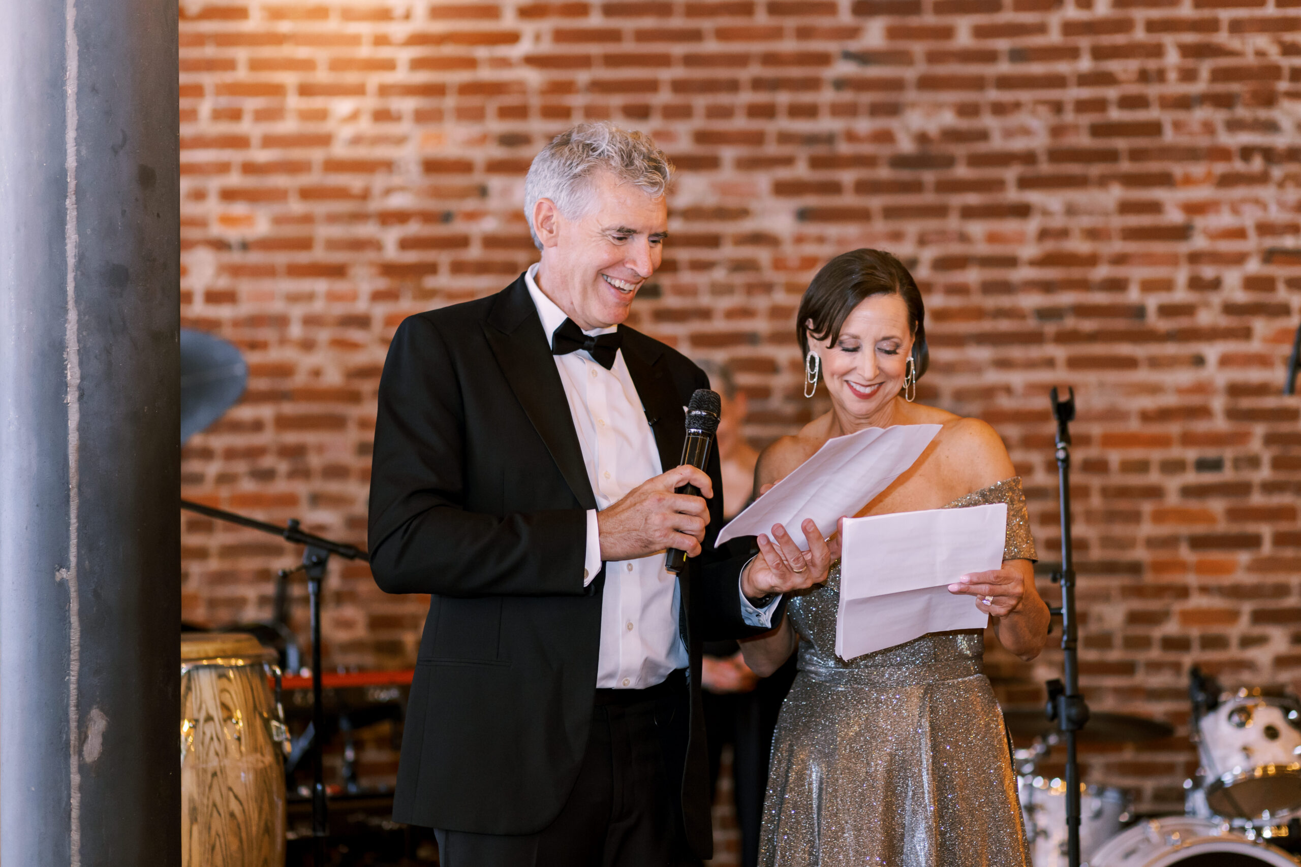Parents giving a toast with a microphone during the wedding reception.