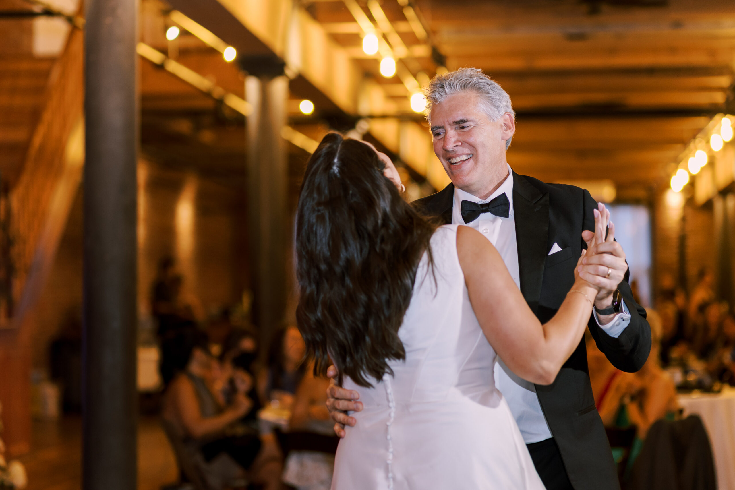 Bride and her father smiling while dancing together on the reception dance floor.