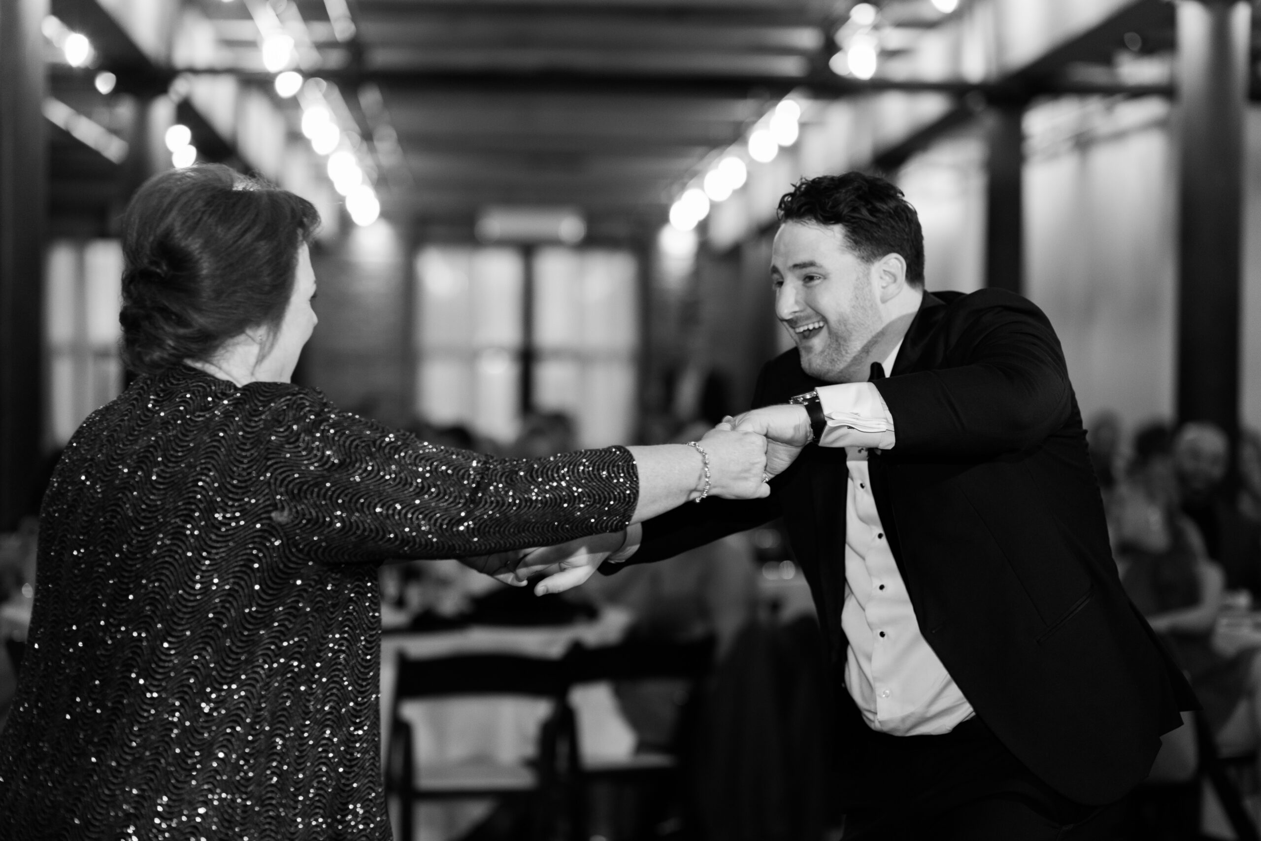 Groom dancing and holding hands with a guest during the reception.