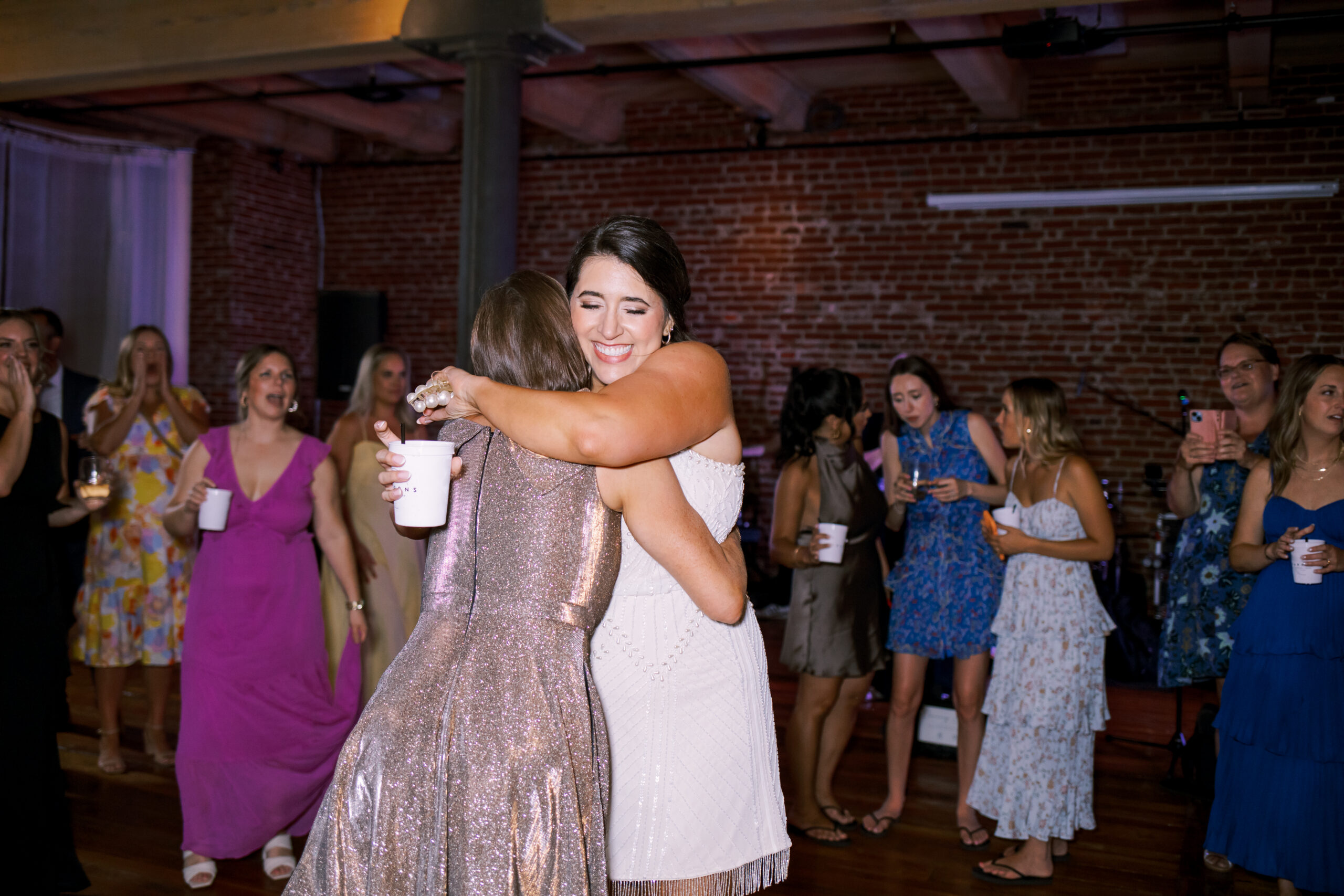 Bride hugging a guest while celebrating on the dance floor during the reception.