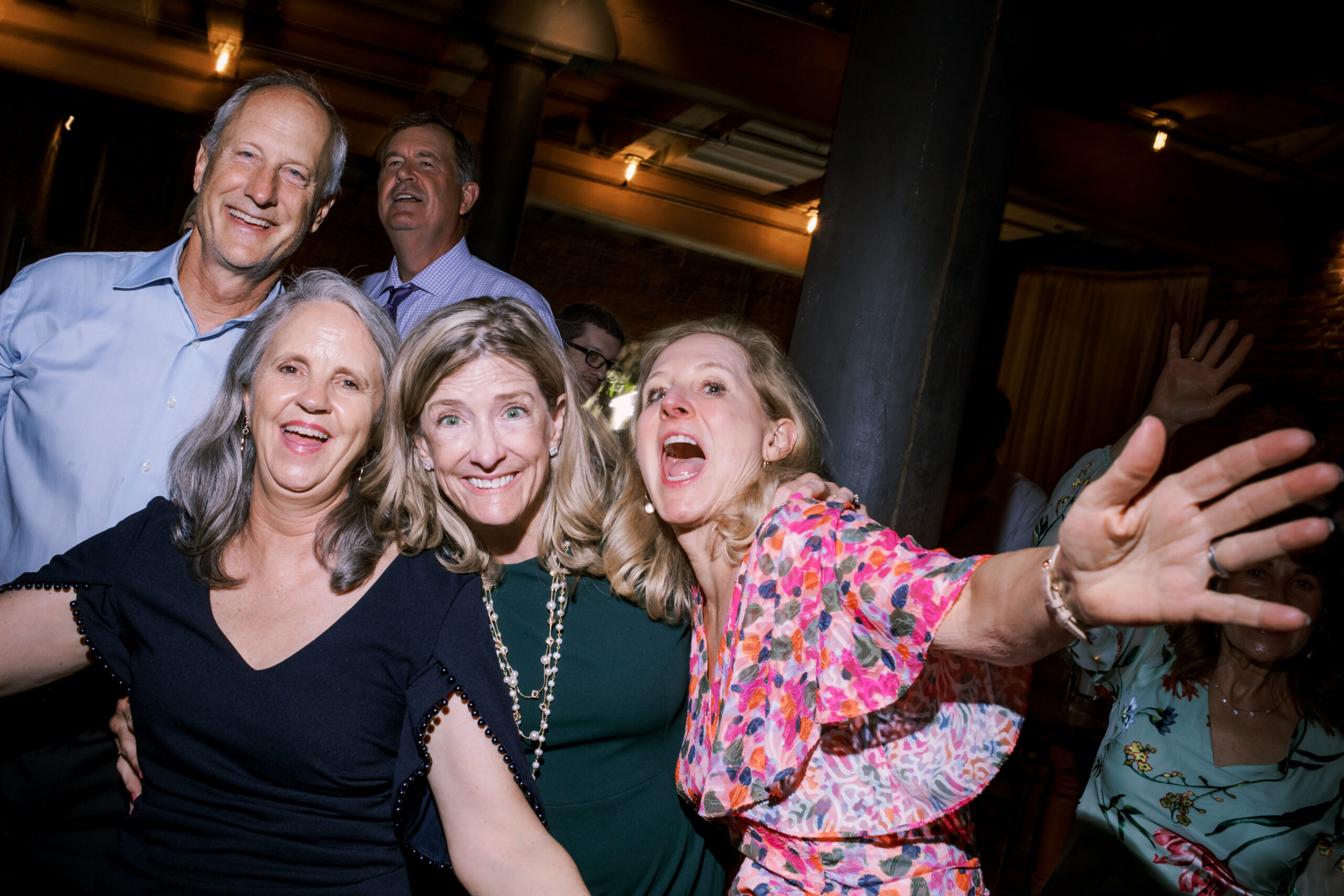Group of five wedding guests smiling and laughing together on the dance floor