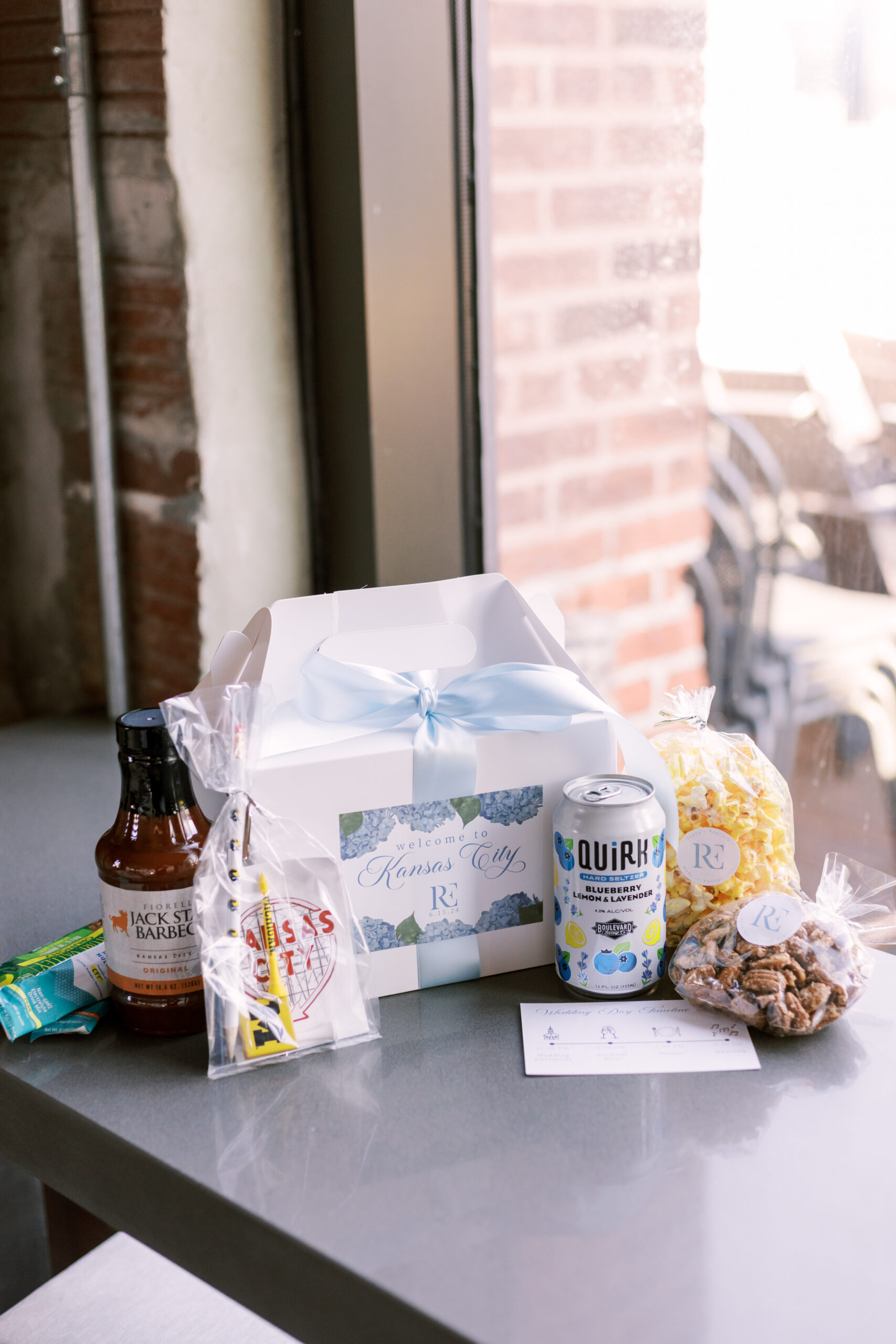 Welcome gift box with snacks, drinks, and Kansas City-themed items arranged on a table.