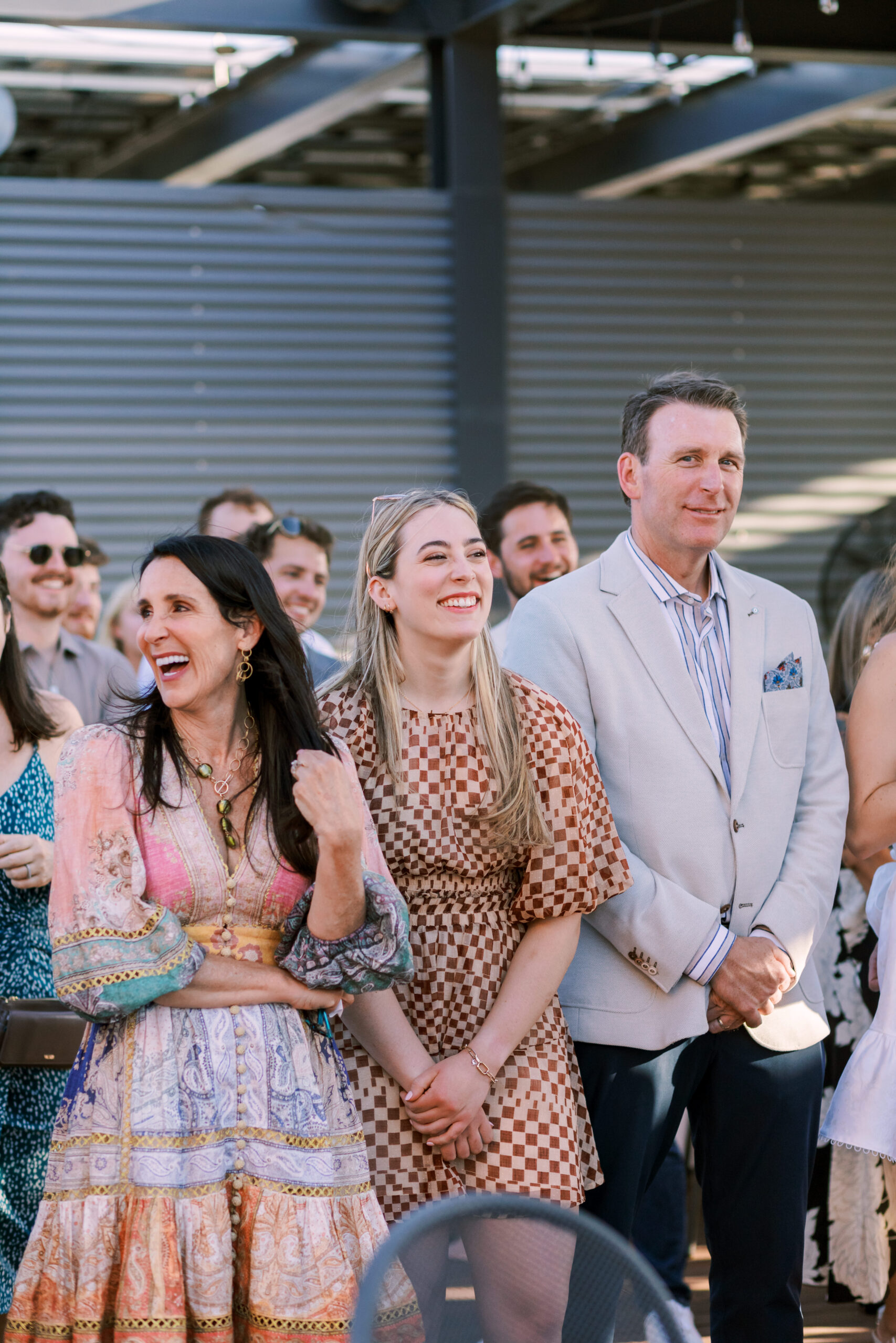 Group of guests standing together, smiling and watching a moment unfold during a rooftop event.