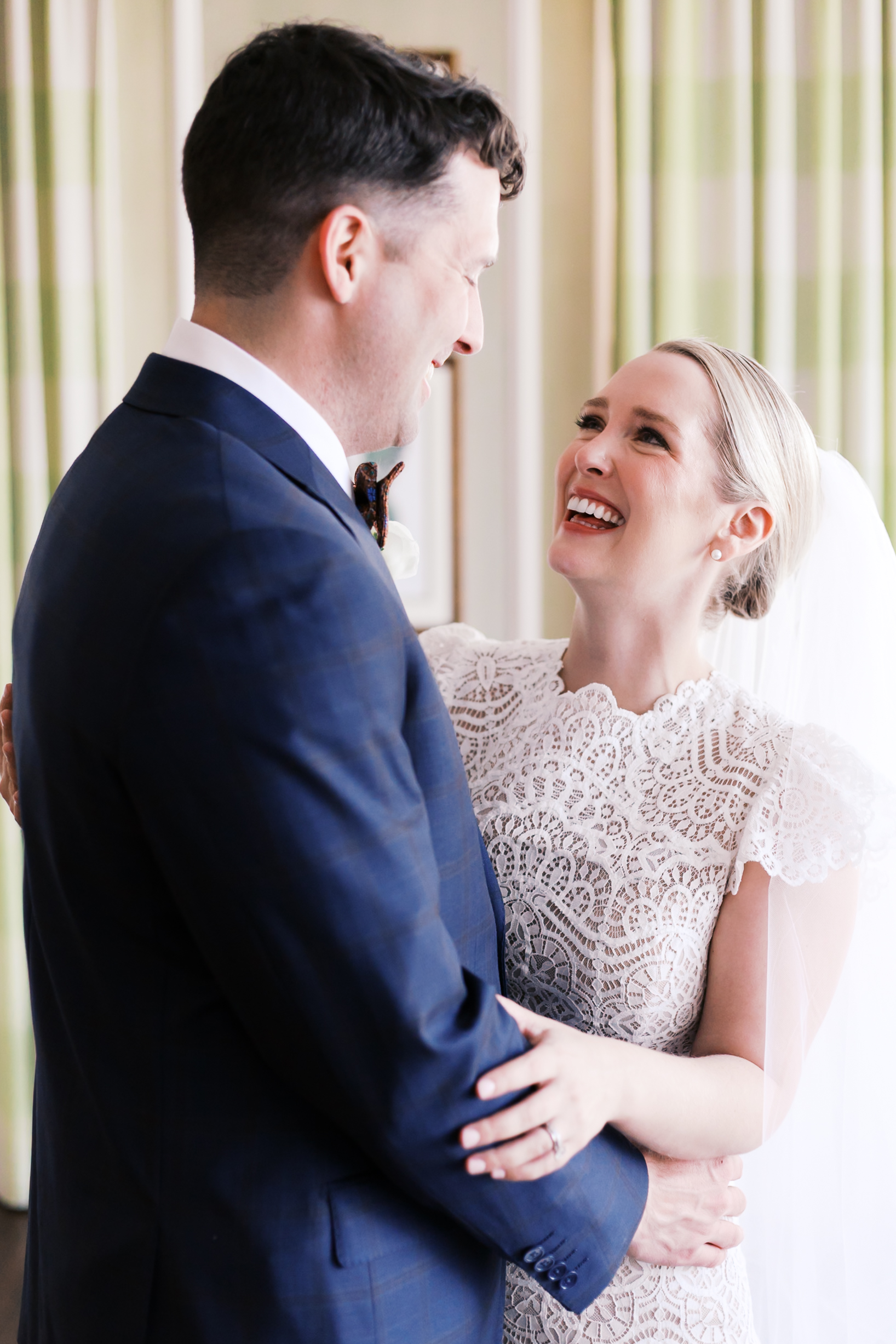 Close-up of bride and groom smiling at each other during wedding portraits indoors.