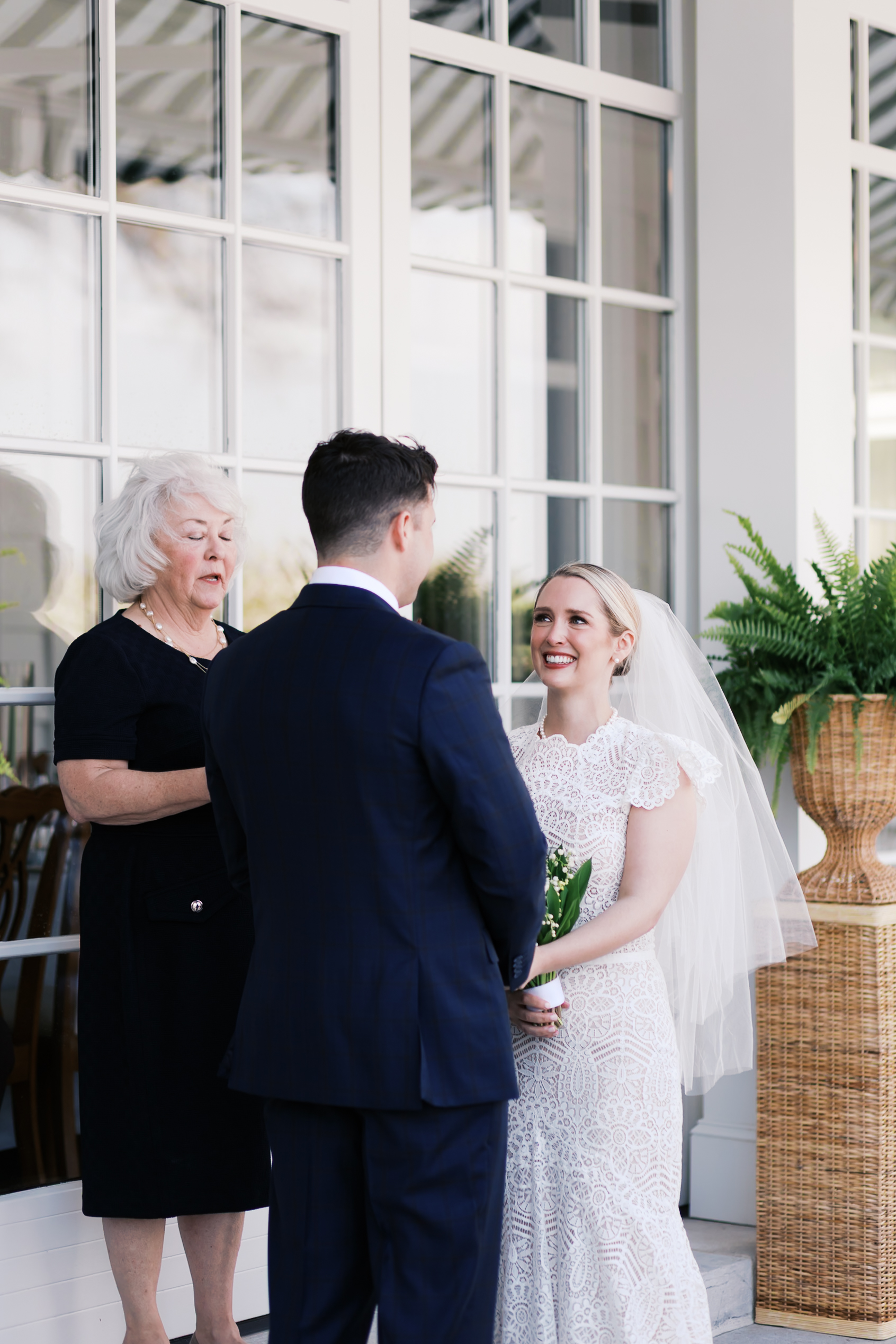 Bride smiling at groom while holding bouquet during wedding ceremony