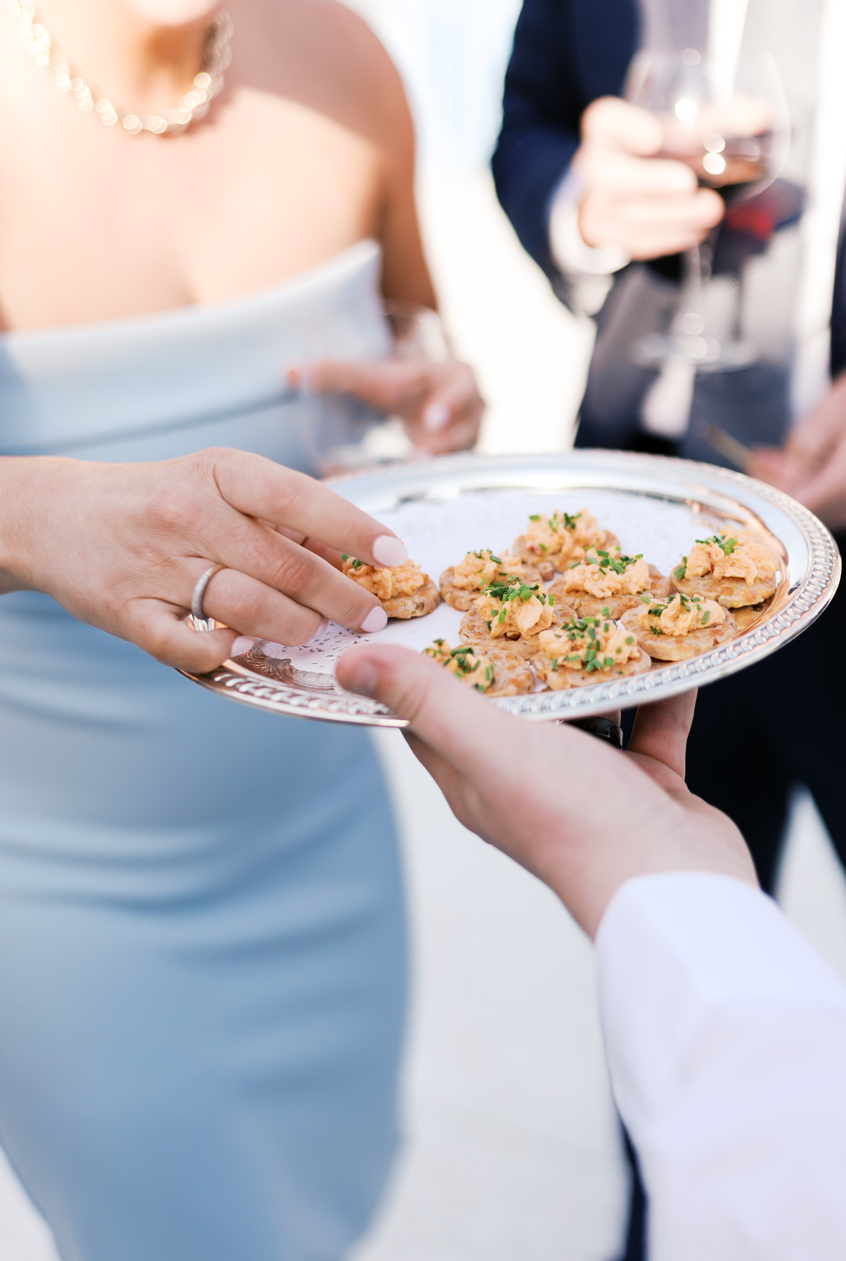 Guest reaching for appetizers on silver tray during wedding reception