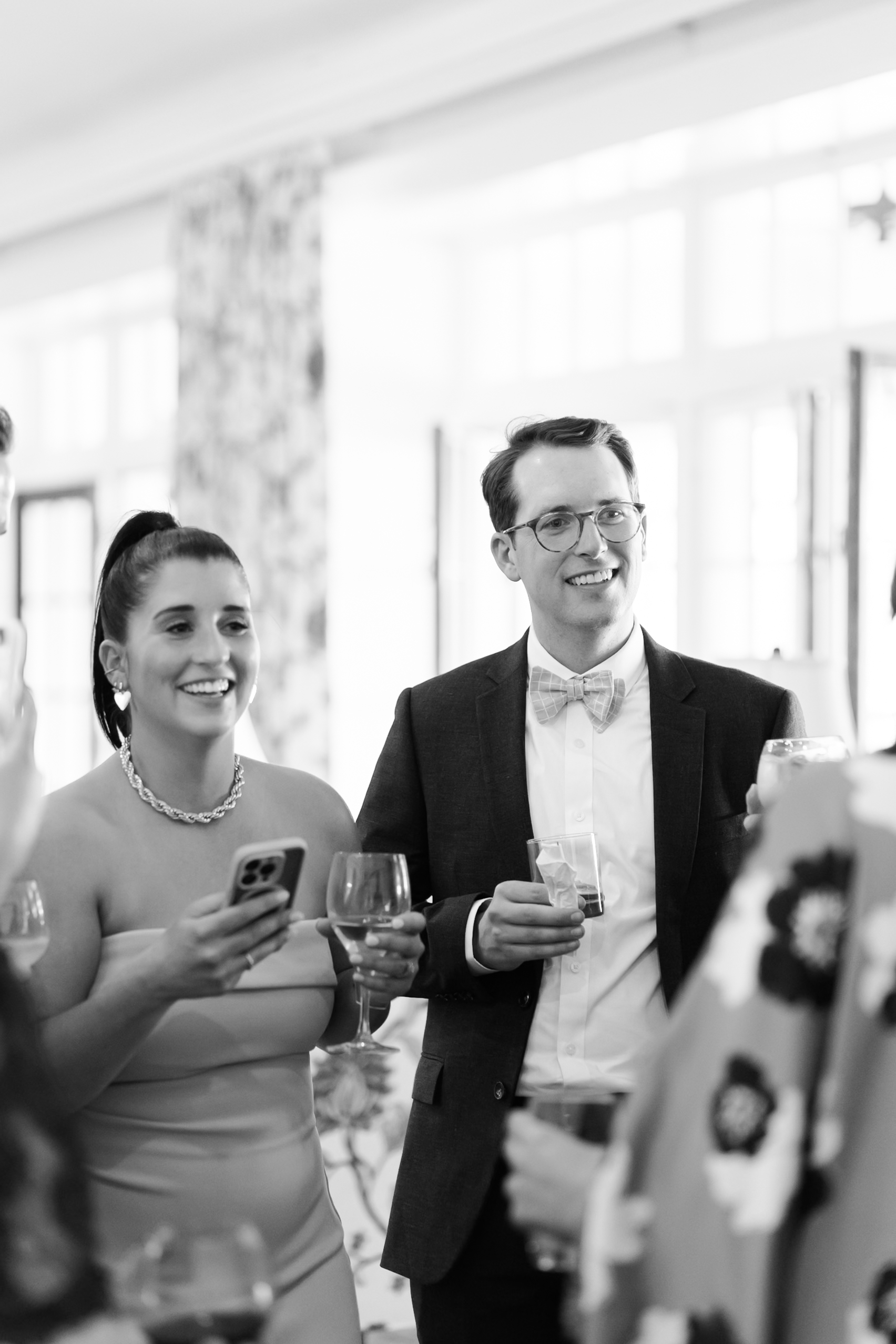 Wedding guests indoors holding drinks and smiling during reception