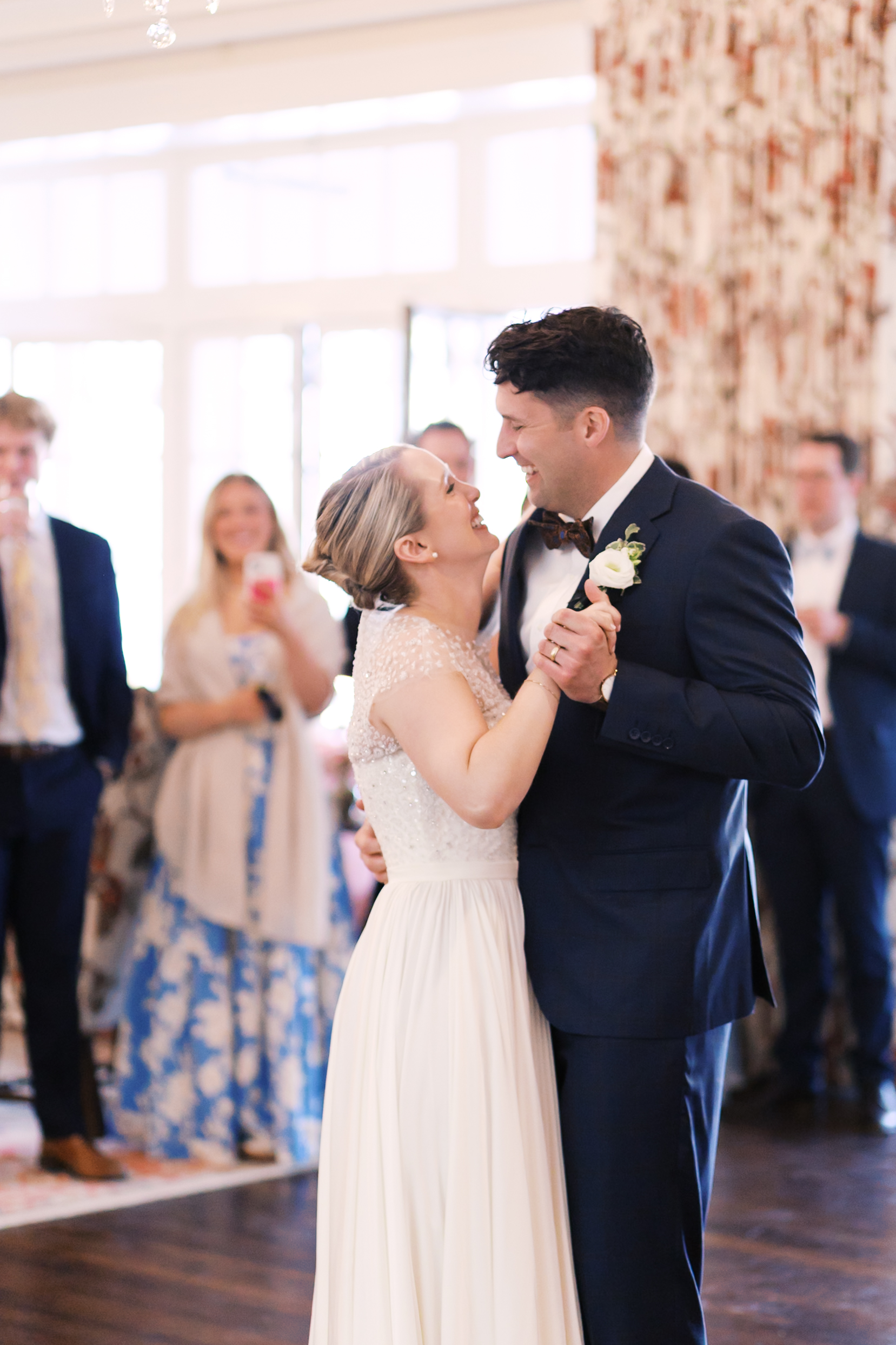 Bride and groom sharing first dance indoors surrounded by guests