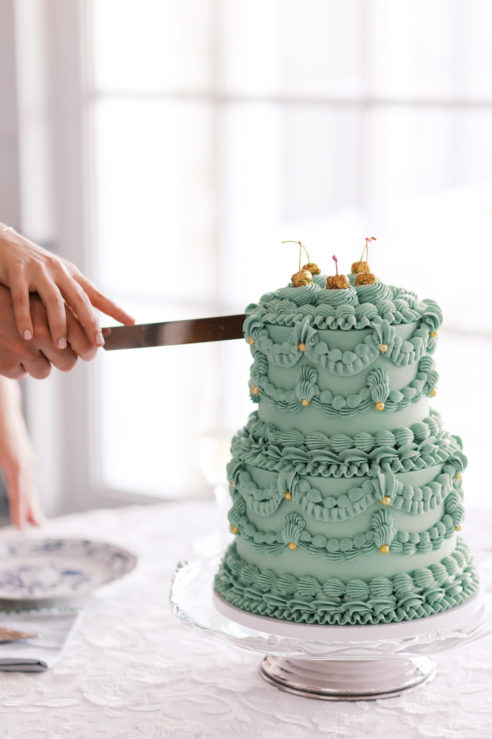 Hand cutting into mint green wedding cake on display table