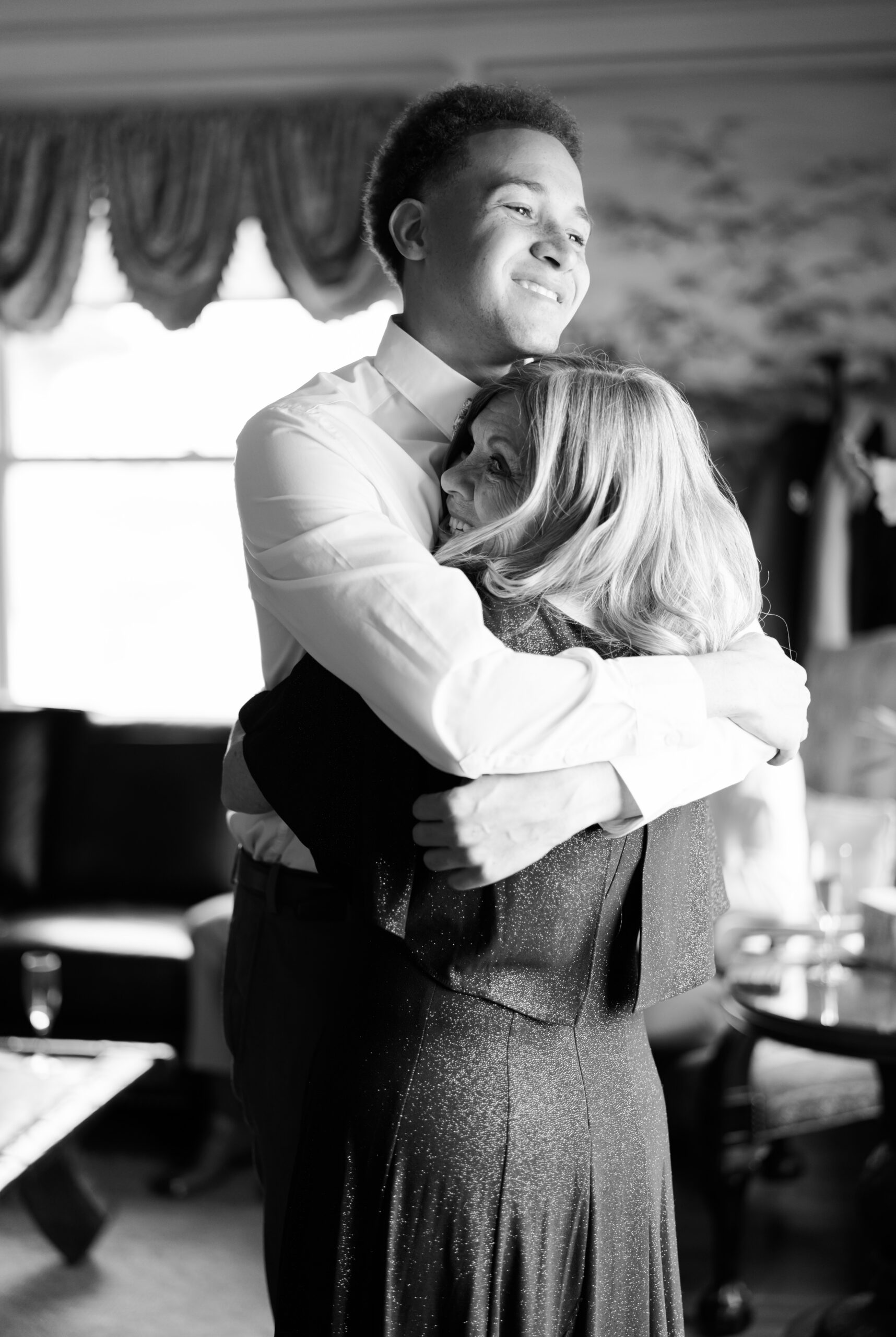 Groom hugging an older woman in a softly lit room before the wedding