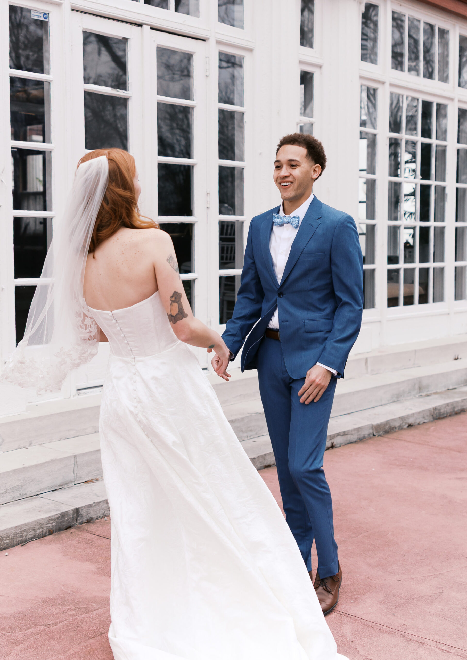 Bride and groom meeting outside Longview Mansion, holding hands in wedding attire