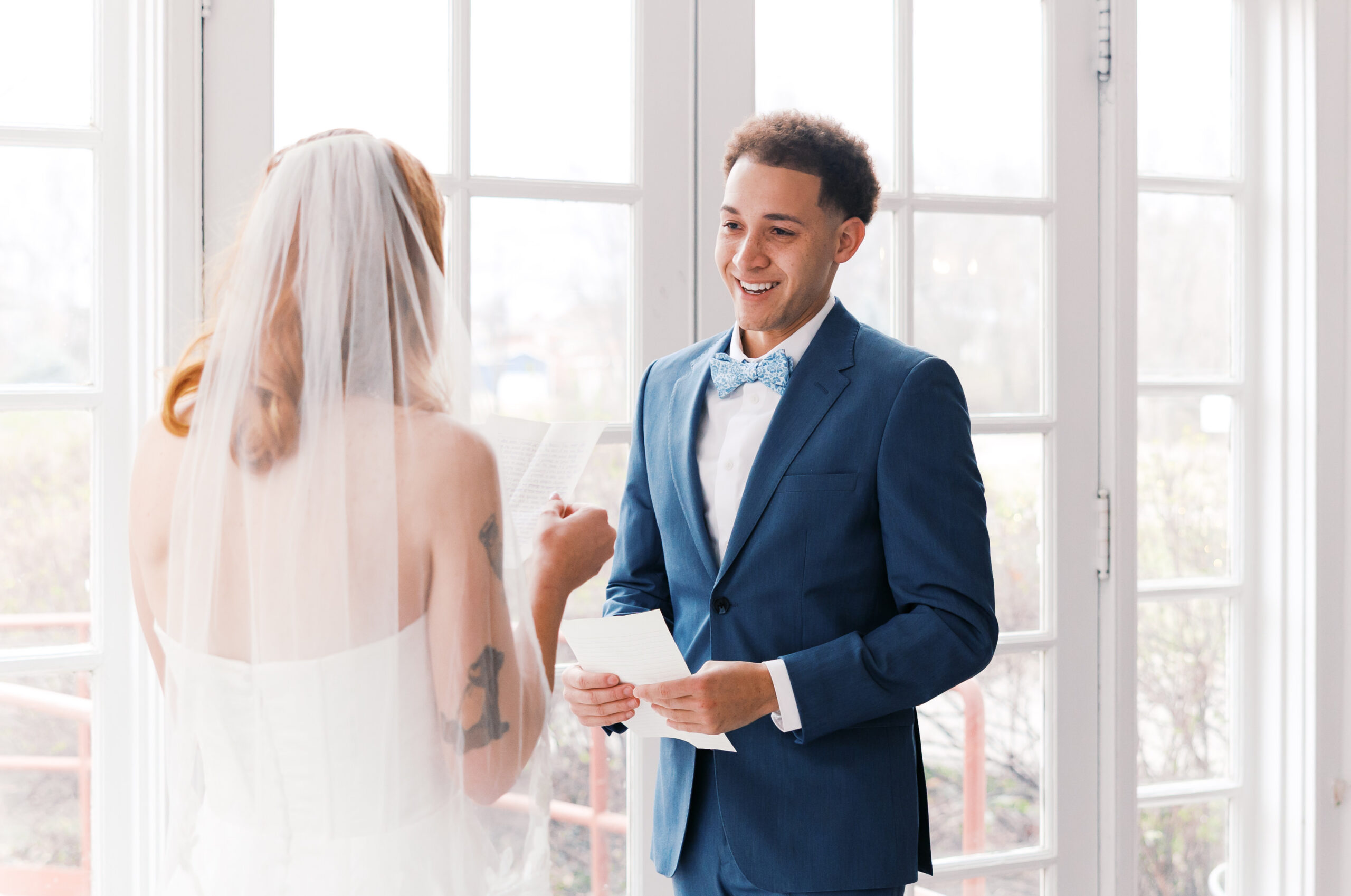 Bride and groom reading vows by window in natural light at Longview Mansion