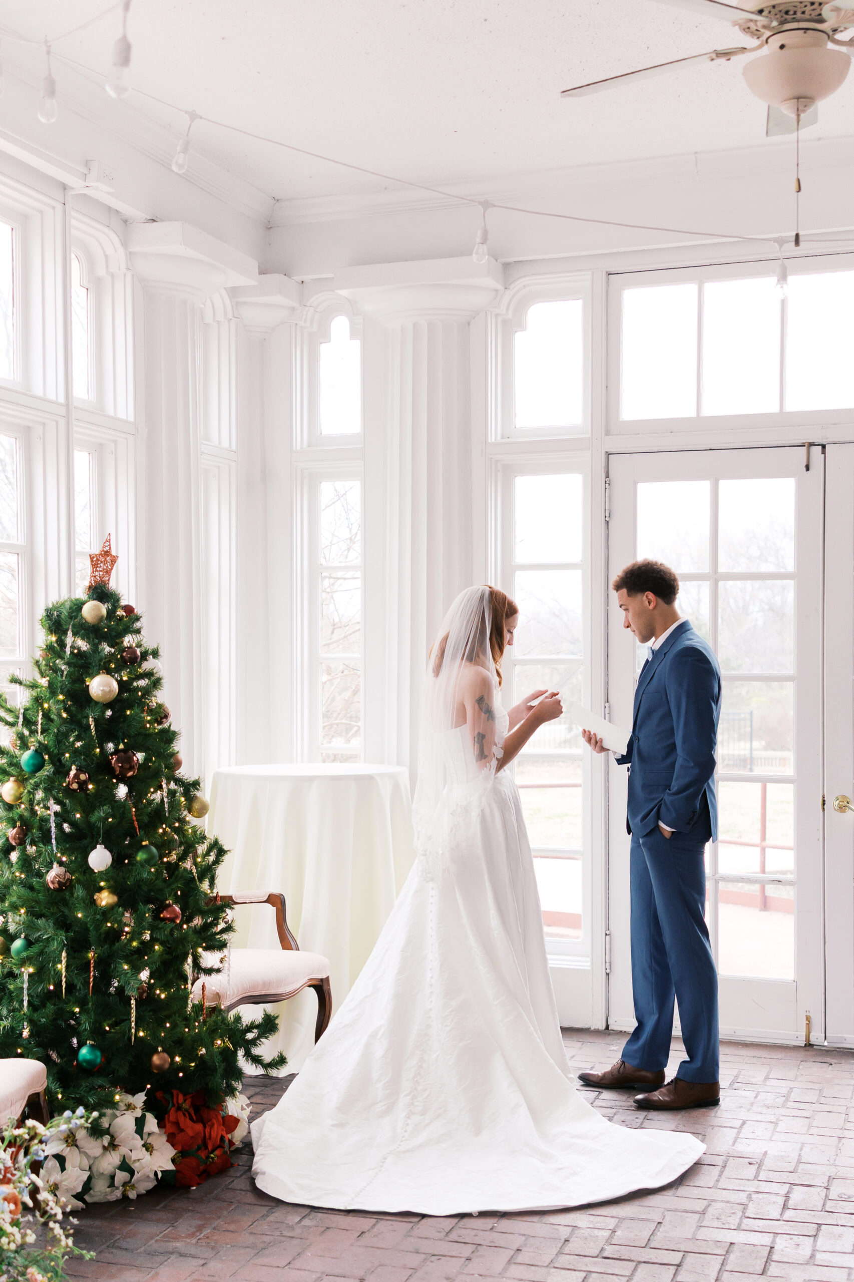 Bride and groom exchanging vows beside decorated Christmas tree at Longview Mansion
