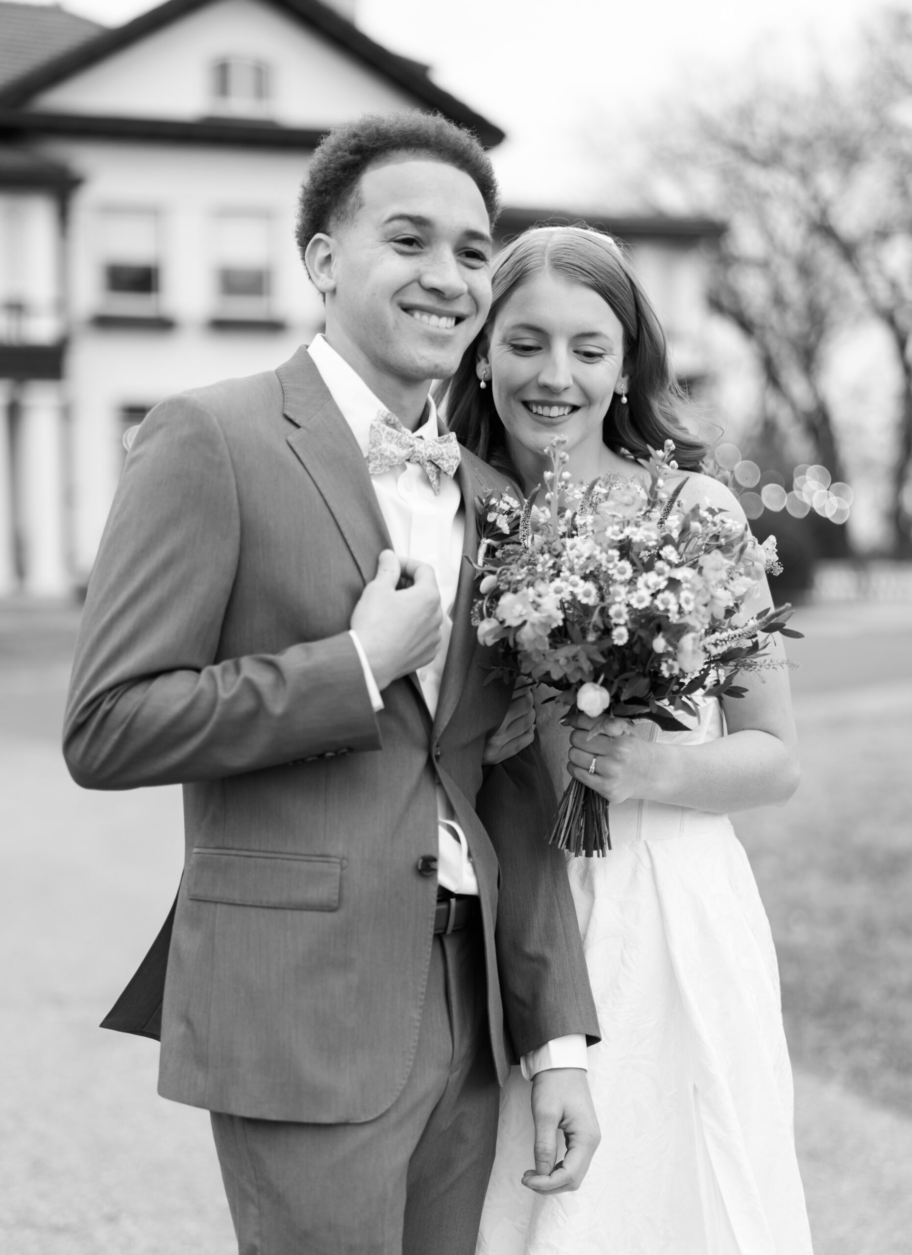 Black and white portrait of bride and groom holding bouquet outdoors