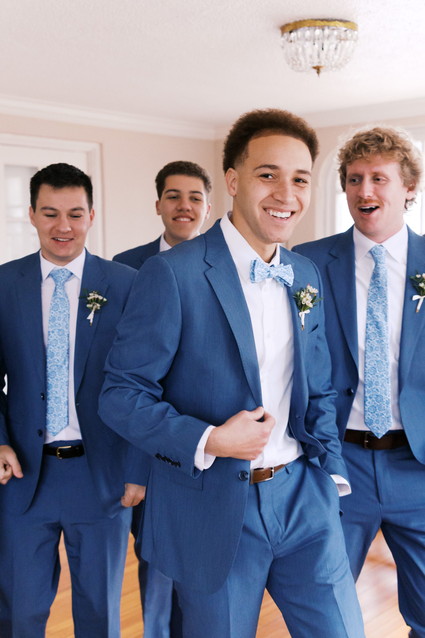 Groom with groomsmen in blue suits getting ready indoors