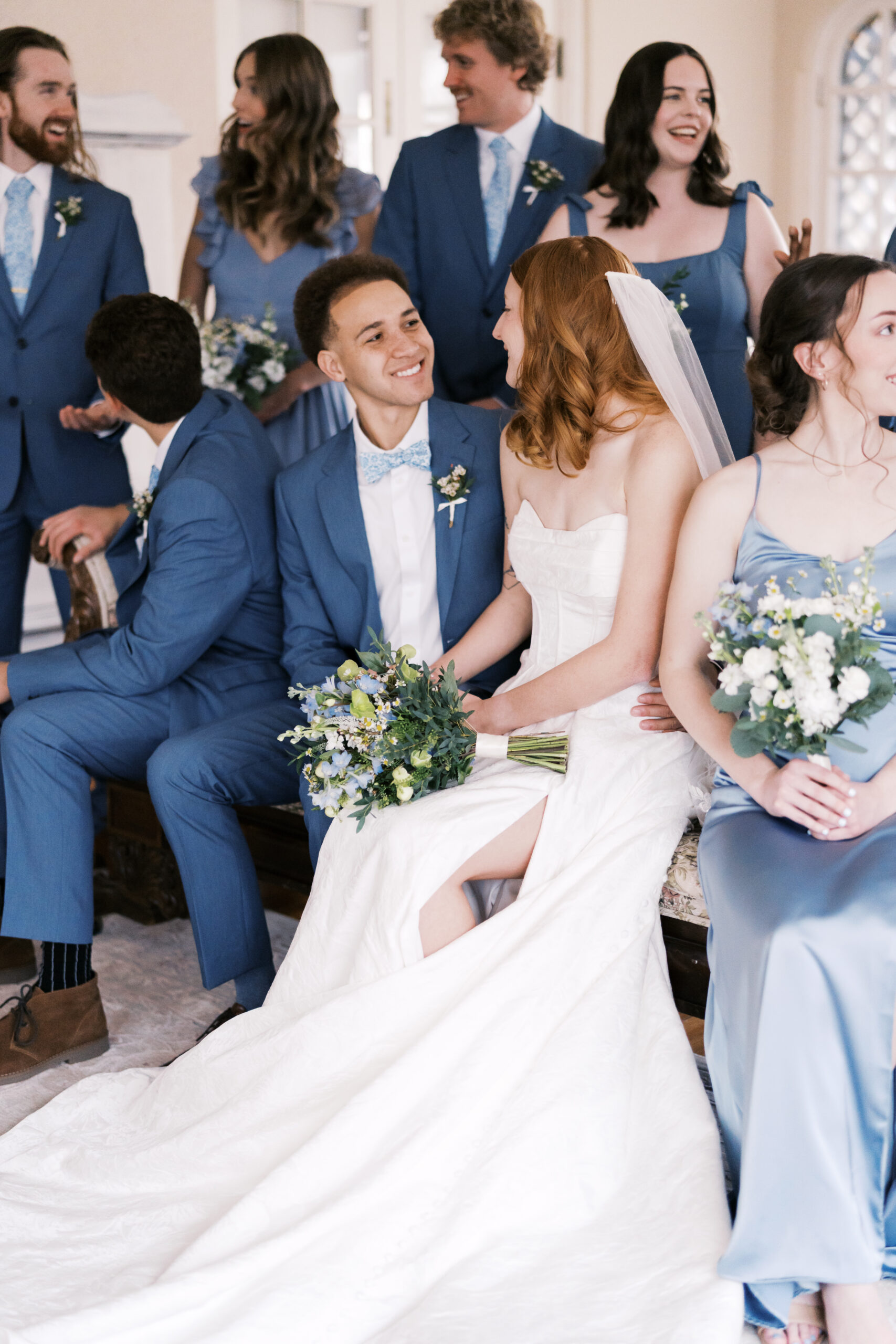 Bride and groom seated with wedding party in coordinated blue attire