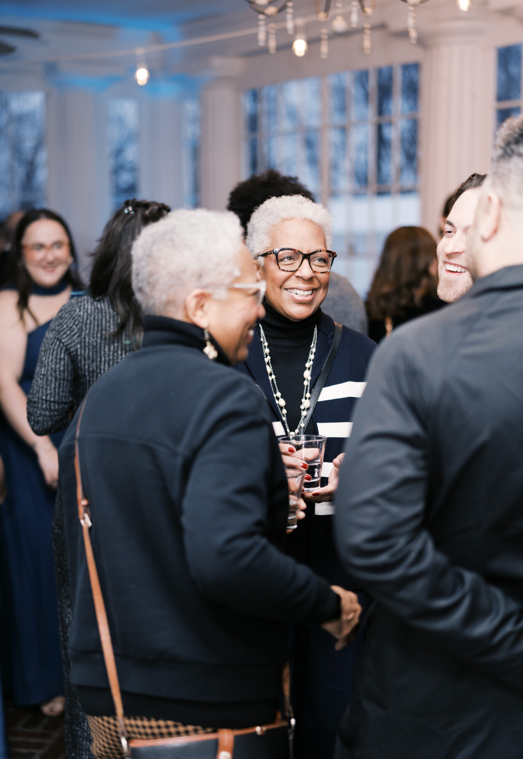 Group of guests smile and converse during cocktail hour.