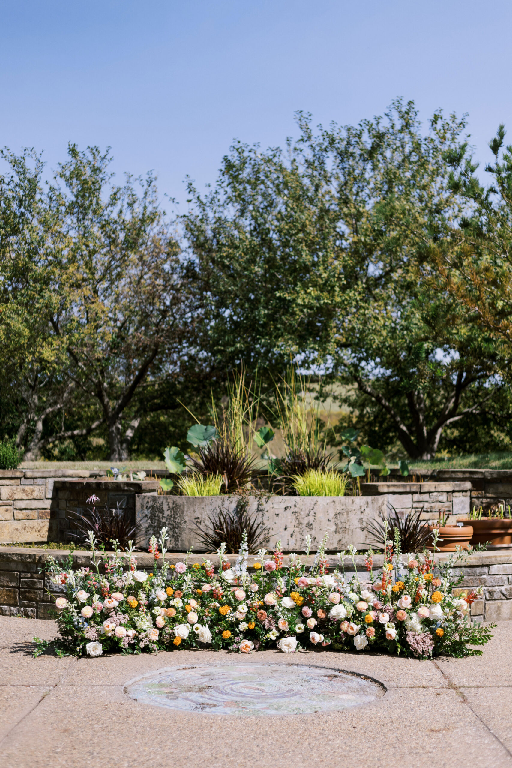 Floral ceremony setup with colorful garden flowers arranged in front of a stone terrace at Powell Gardens