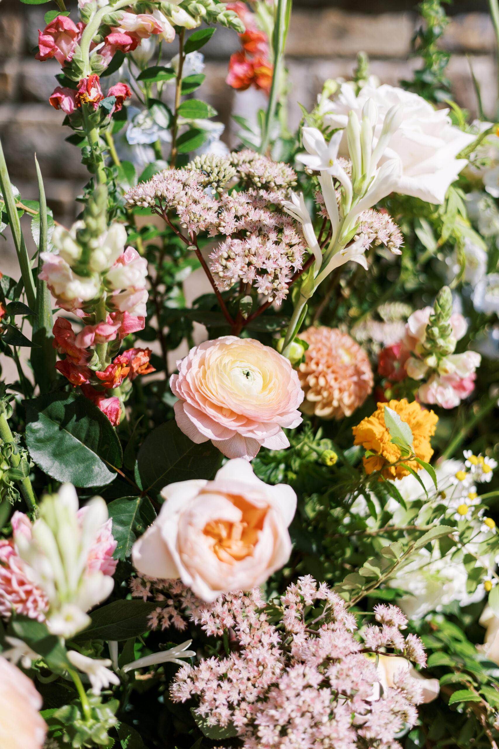 Close-up of pastel garden flowers including roses and ranunculus in a lush floral arrangement.