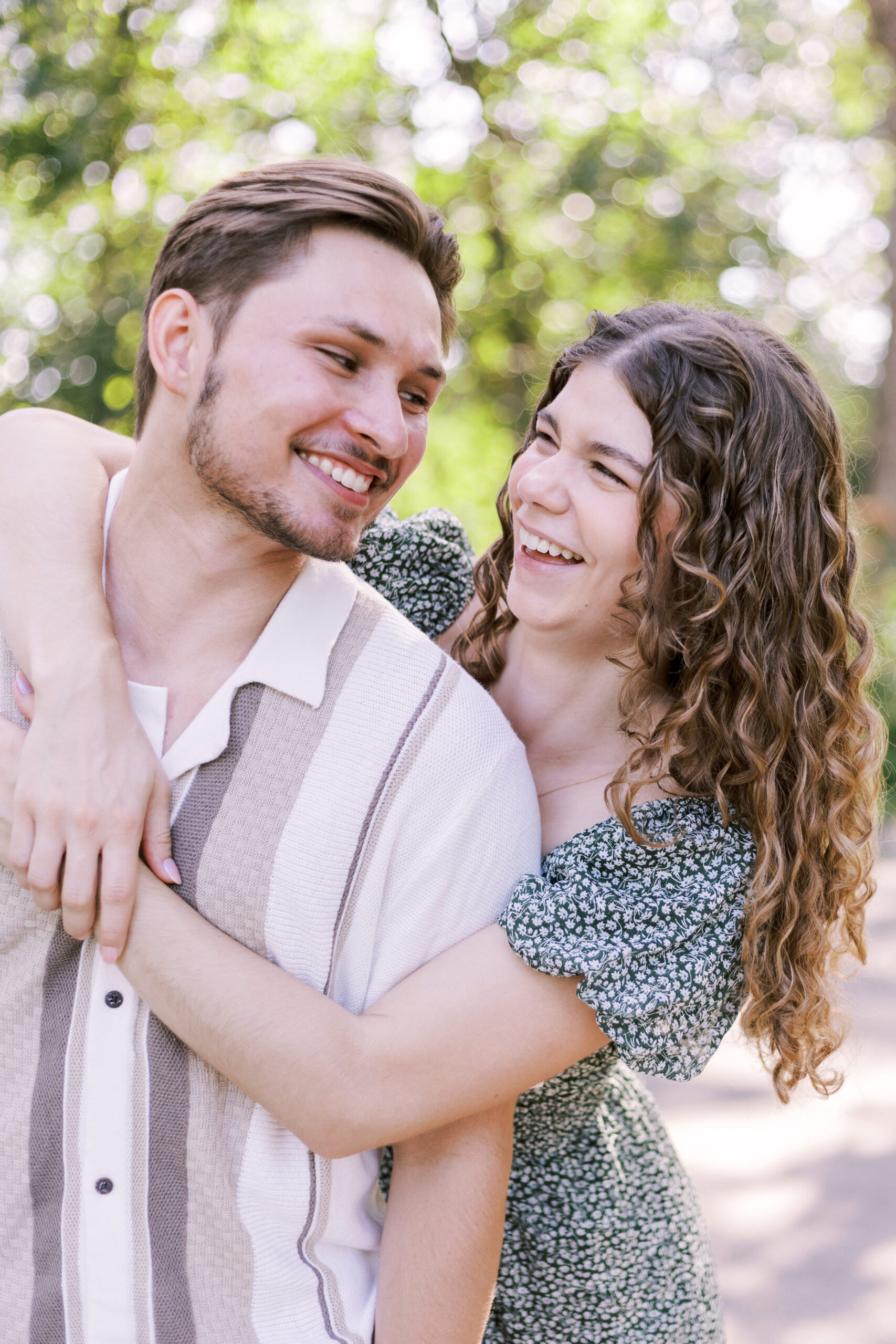 Close-up of couple smiling and embracing after engagement in natural garden light.