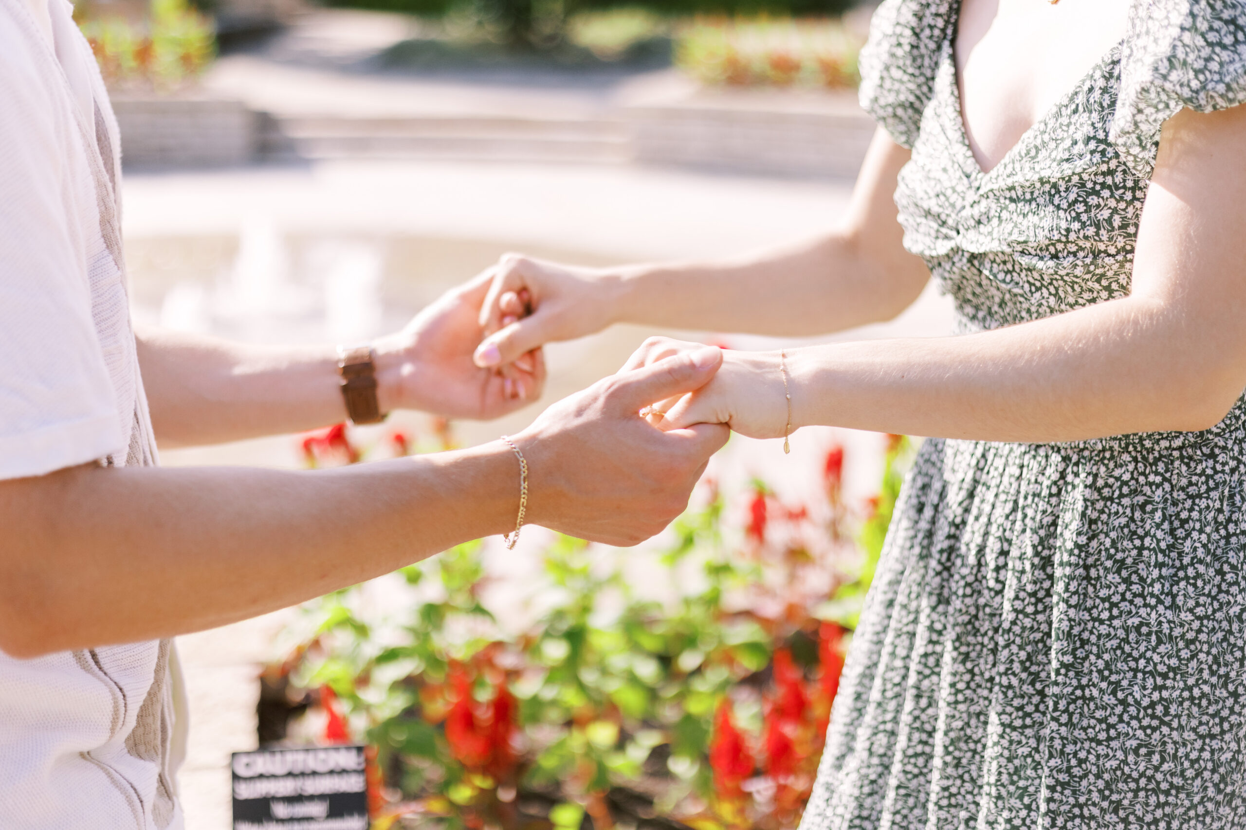 Close-up of couple holding hands as engagement ring is placed during garden proposal at Powell Gardens.