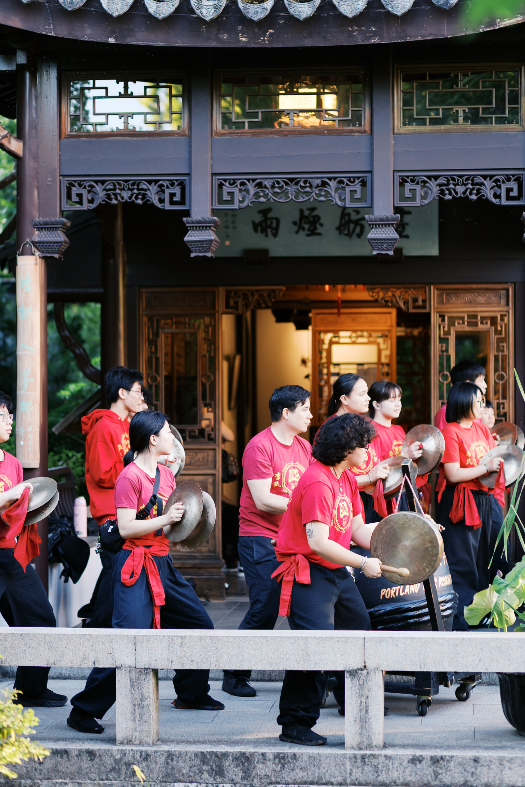 Traditional Chinese percussion group performing with cymbals and drums outside a pavilion during wedding festivities.