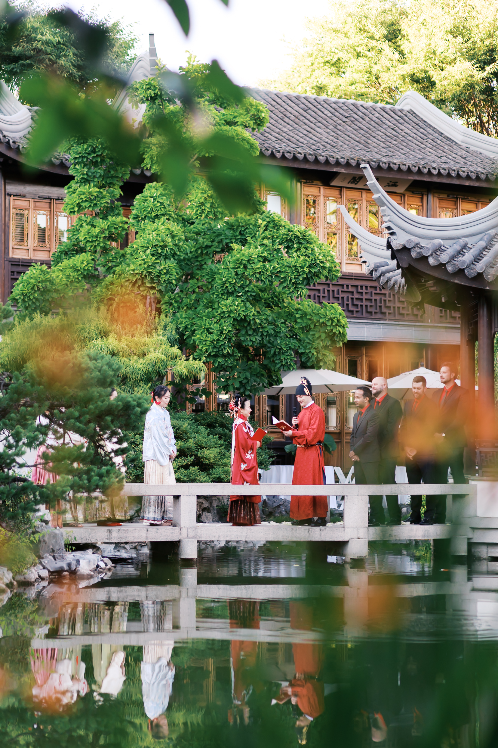Bride and groom exchanging vows on a bridge during a traditional Chinese-inspired outdoor wedding ceremony.