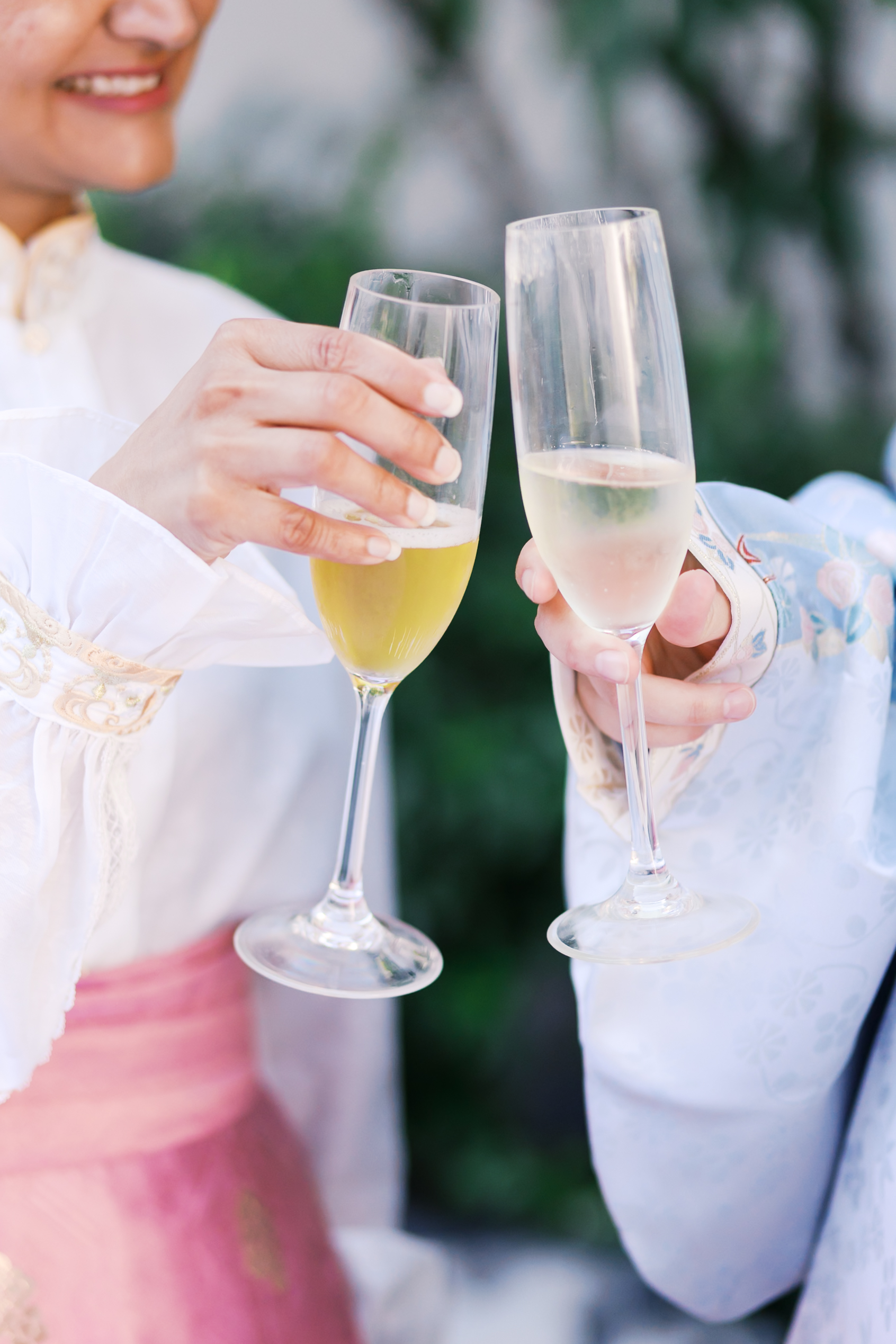 Guests in traditional hanfu attire clink champagne flutes during an outdoor Chinese wedding reception.