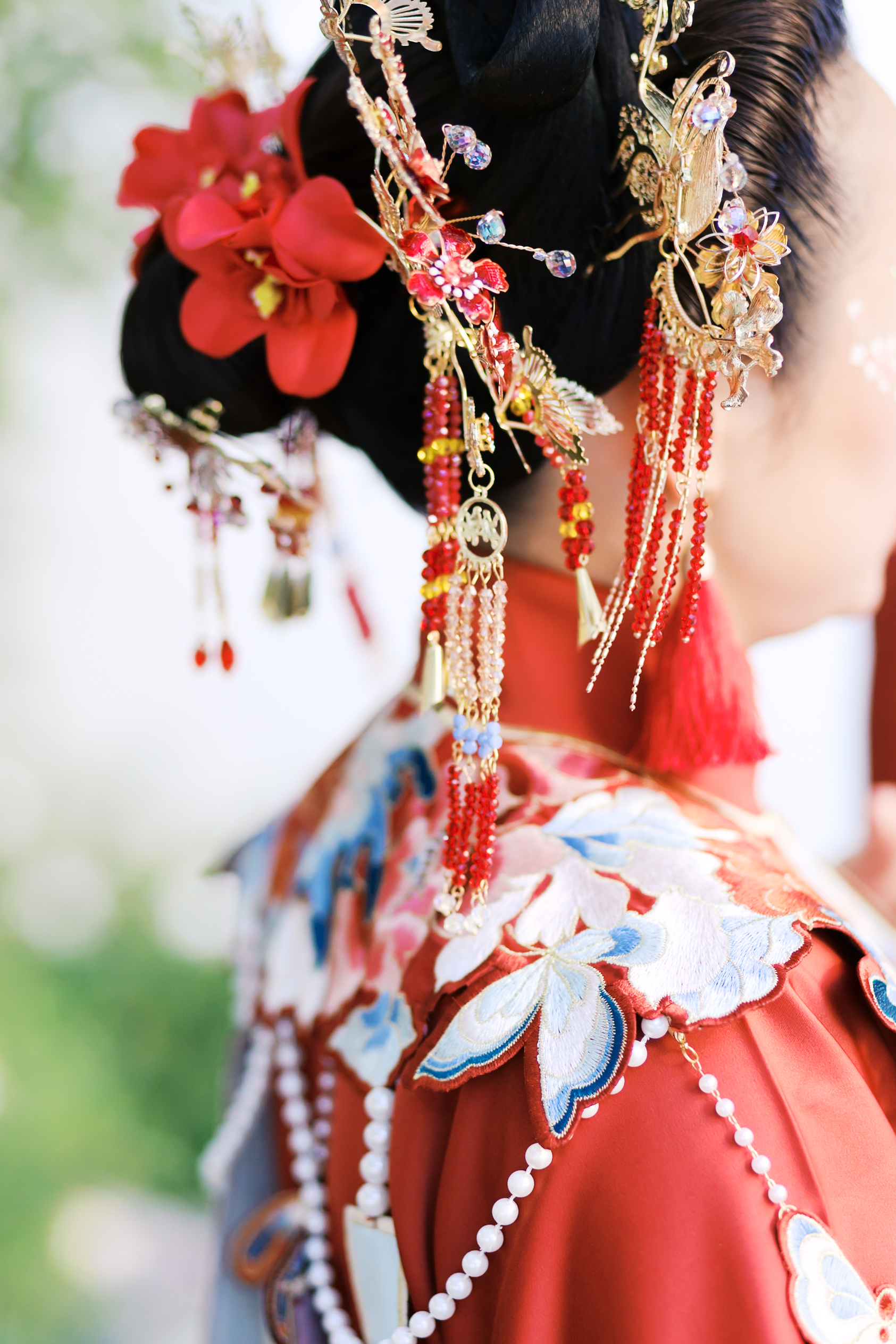 Close-up of intricate red and gold bridal hair ornaments with floral details and dangling beads.