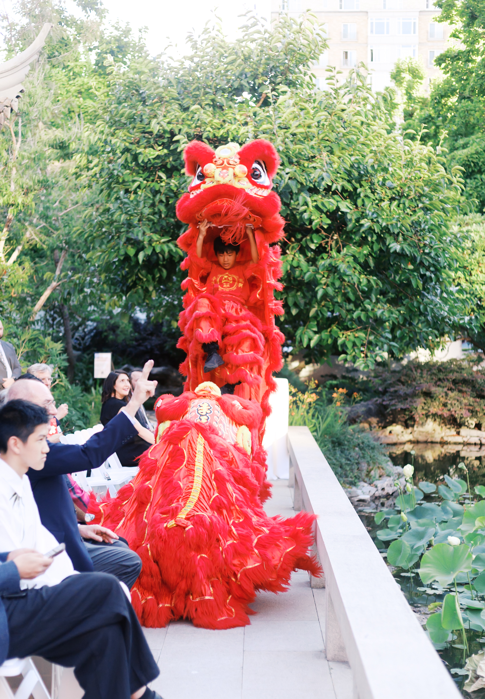 Traditional red lion dance performance entertaining guests at an outdoor Chinese wedding celebration.