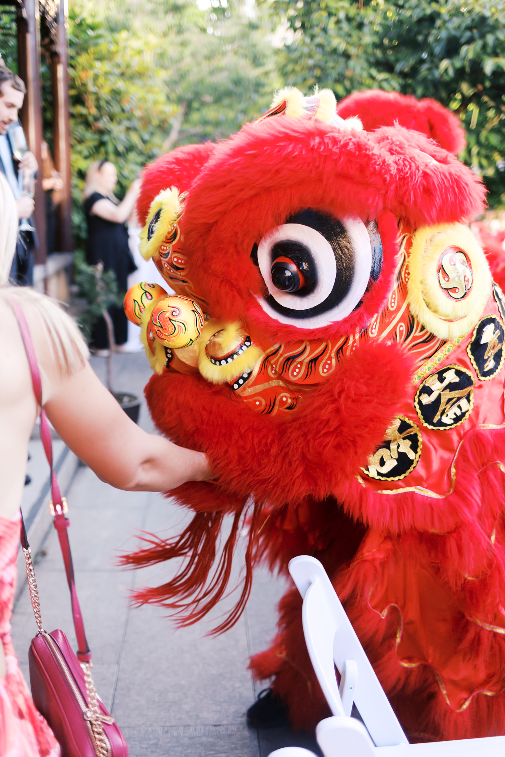 Close-up of vibrant red lion dance costume interacting with guests during wedding festivities.