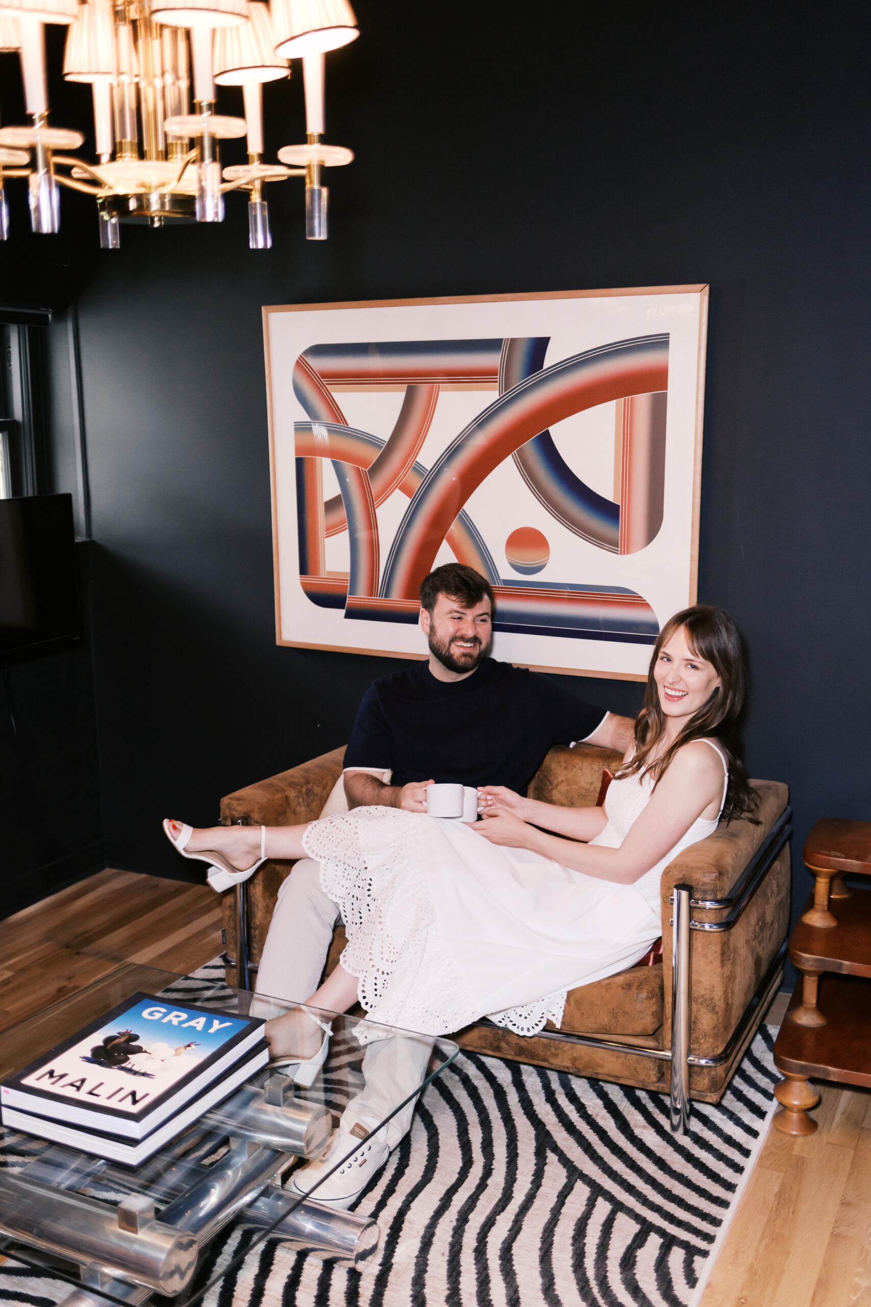 Couple relaxing with coffee together in a cozy hotel lounge during a date night engagement session.