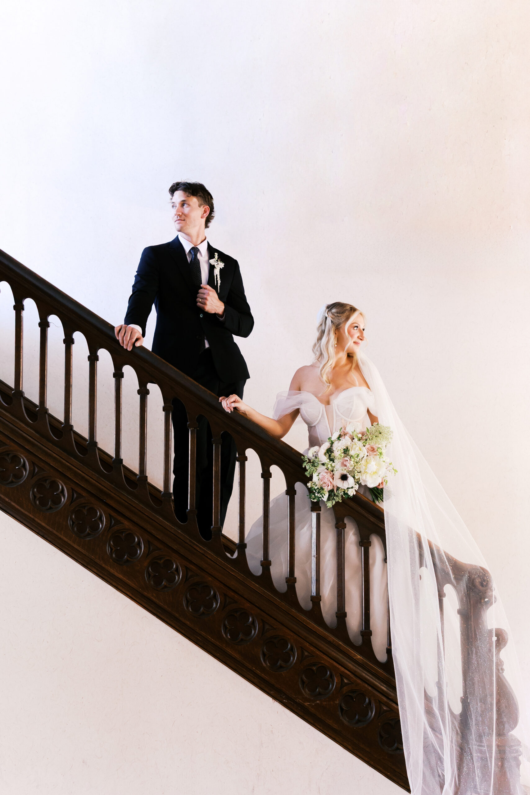 Bride and groom posed on a historic wooden staircase during their Simpson House wedding portraits.