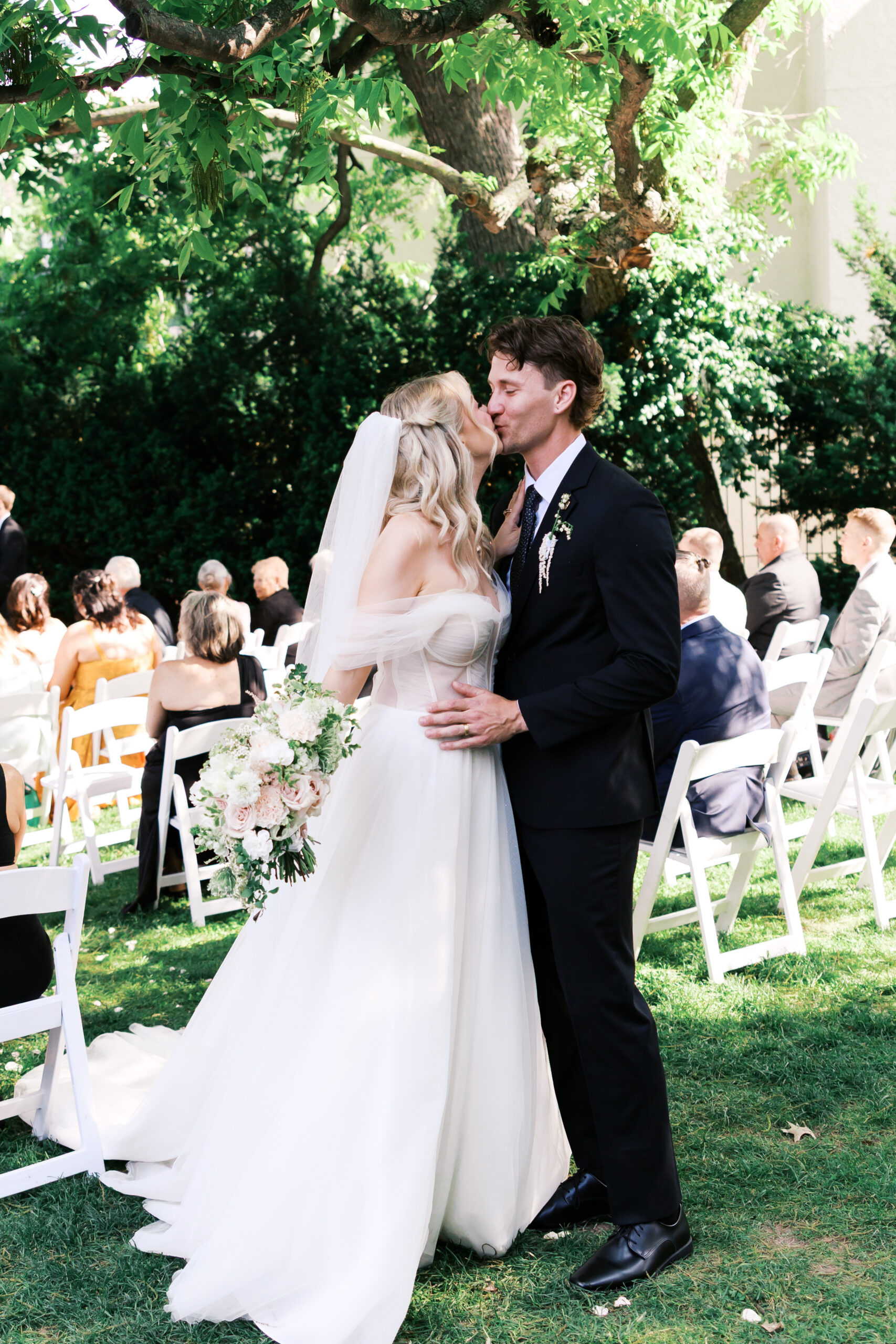 Bride and groom sharing a kiss during an outdoor Simpson House wedding ceremony.