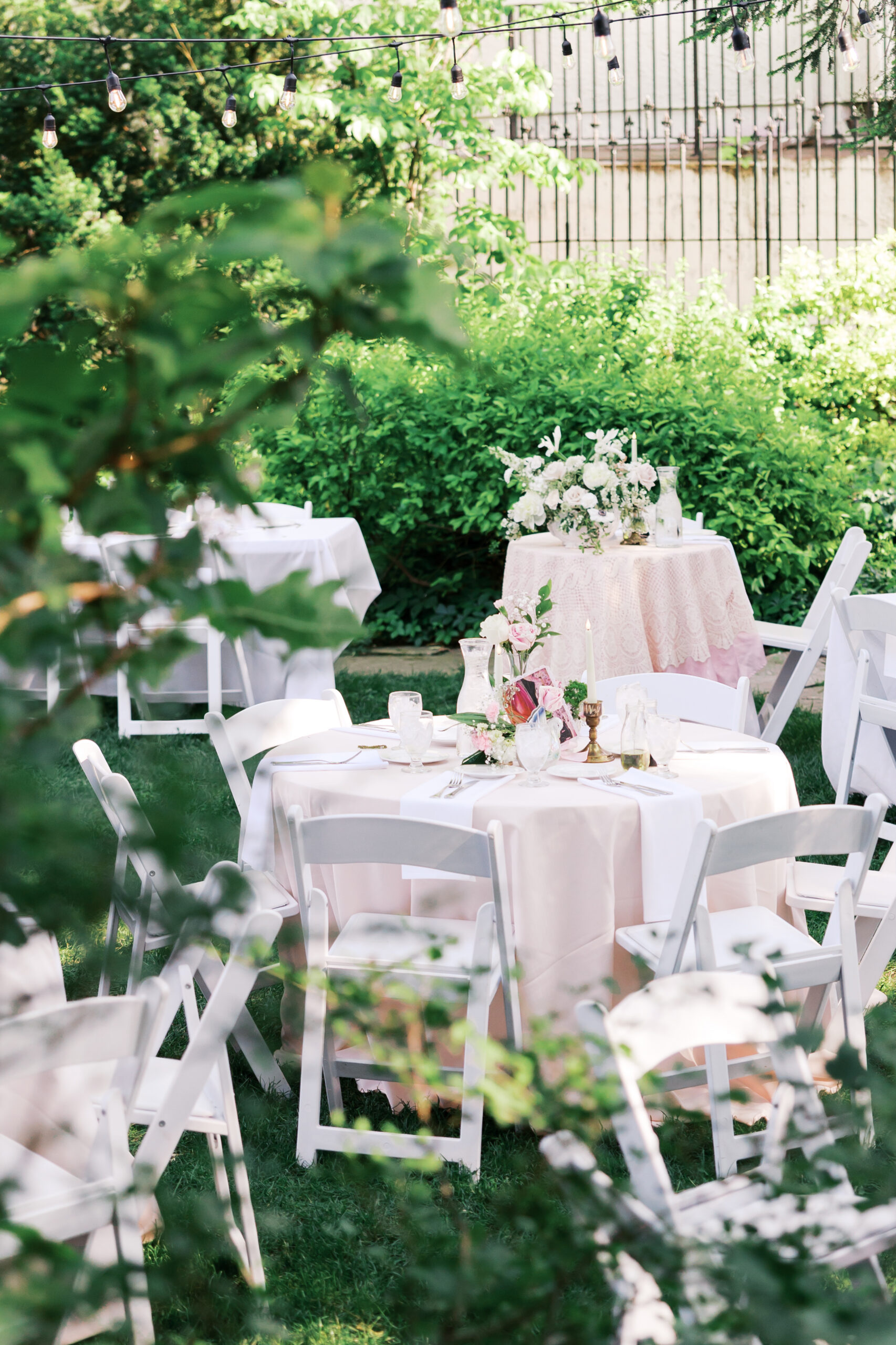 Garden wedding reception tables with blush linens, white chairs, and floral centerpieces at Simpson House.