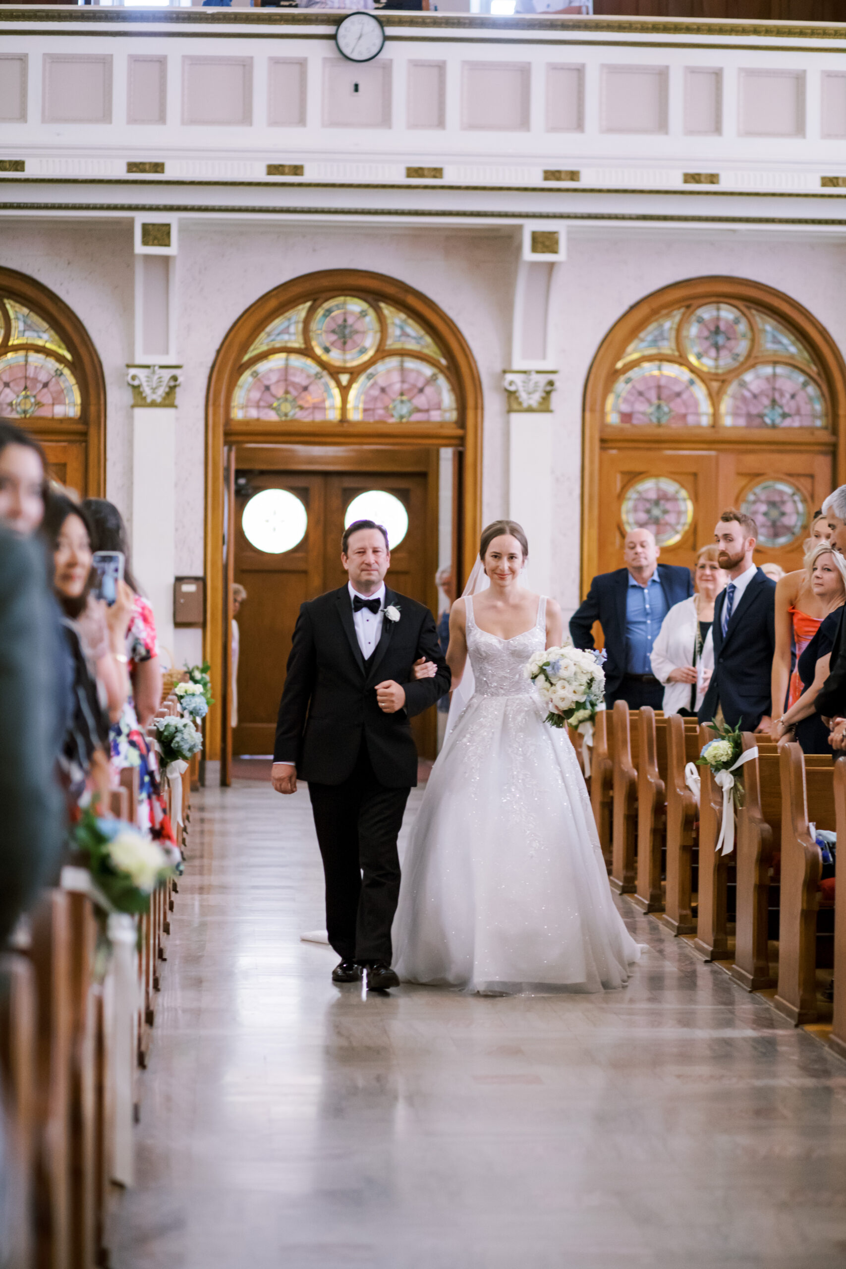 Bride walking down a church aisle with her father during a traditional wedding ceremony.