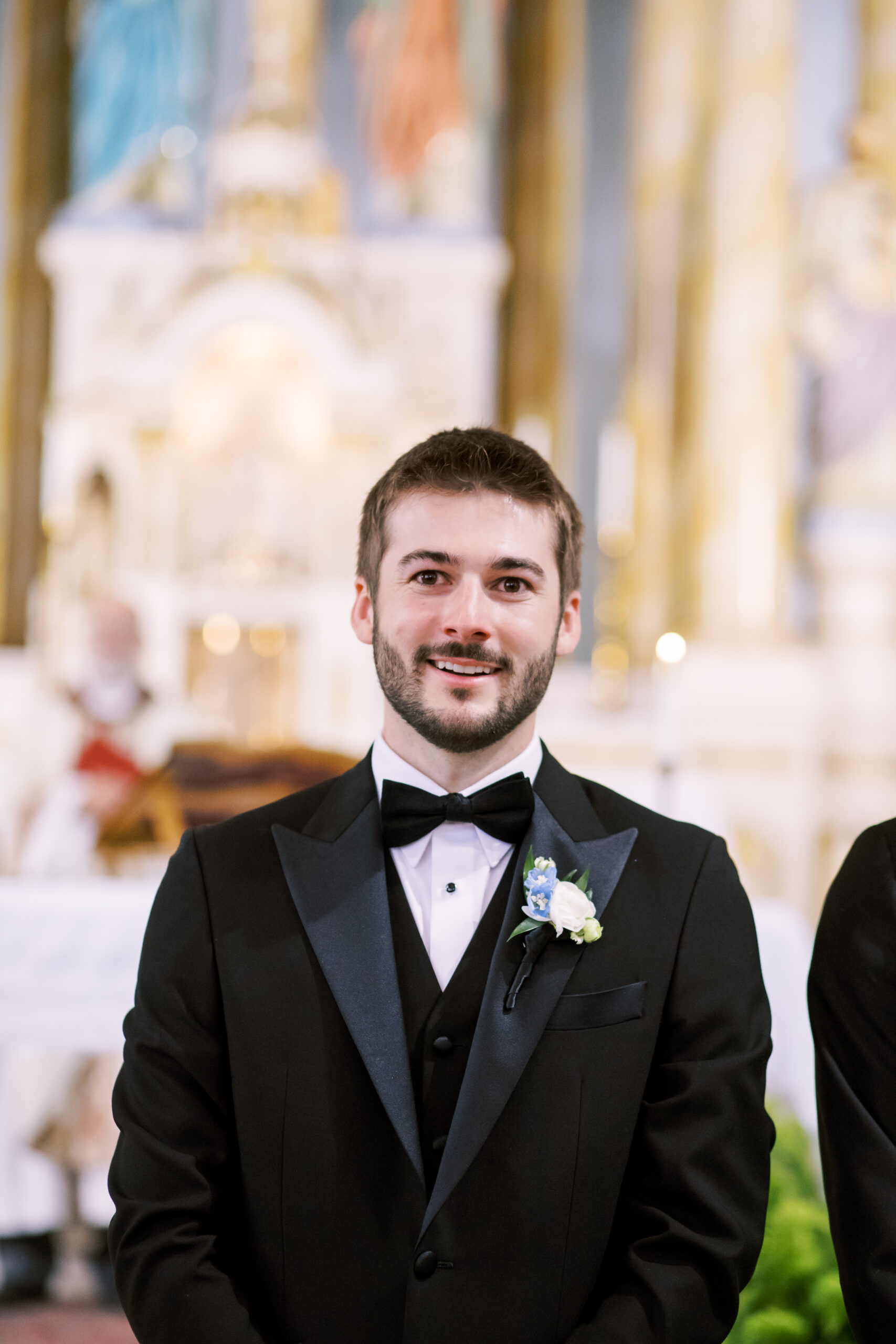Groom in a black tuxedo standing at the altar during a church wedding ceremony.