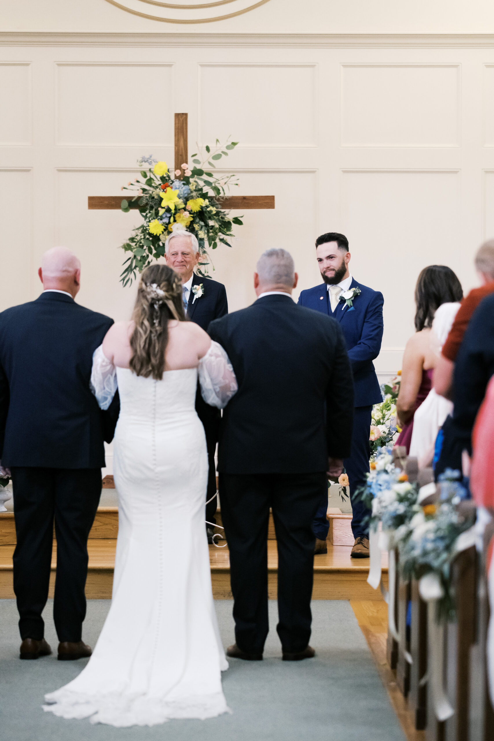 Bride and groom standing at the altar during a church wedding ceremony with guests nearby.