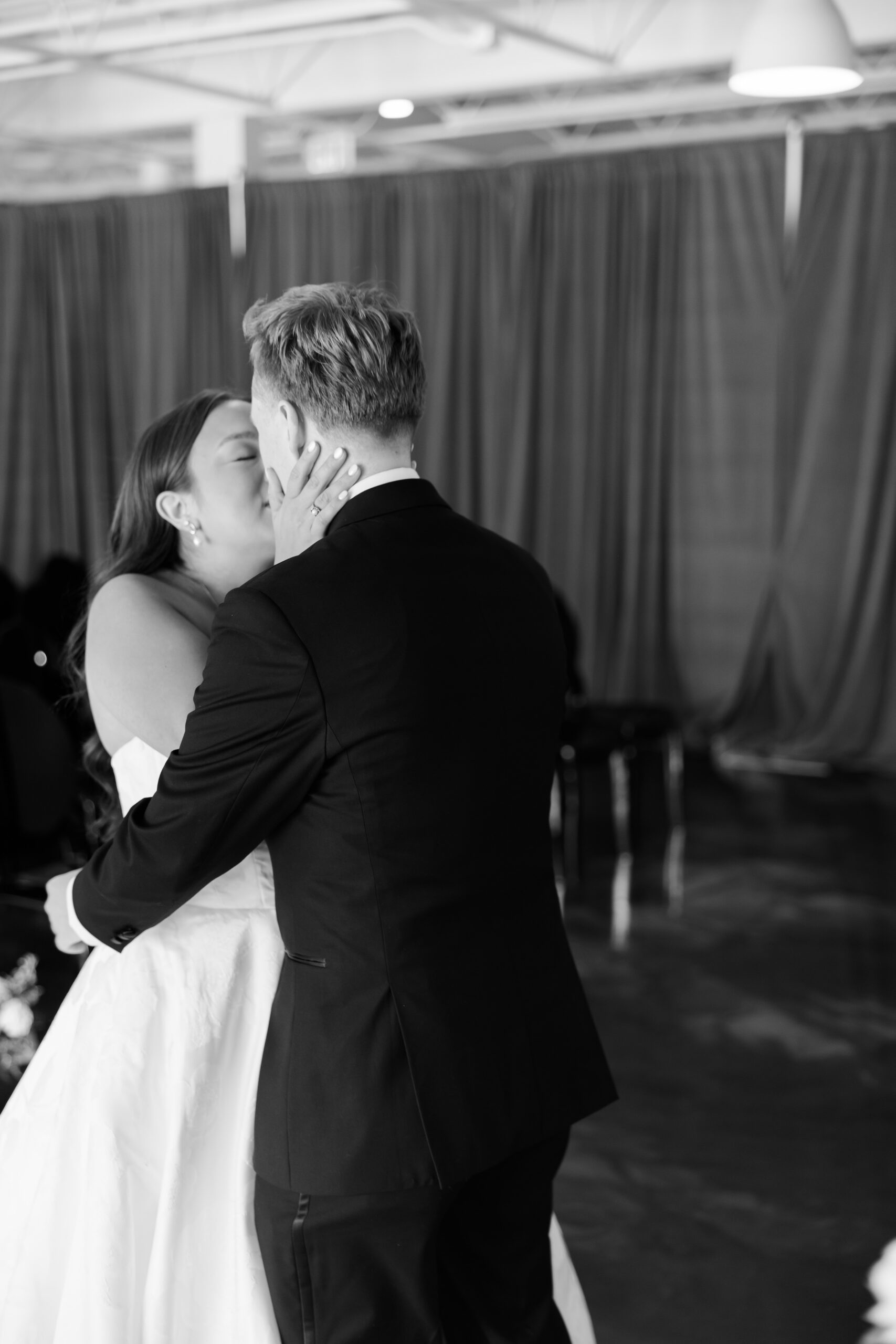 Bride and groom sharing a kiss during a black and white indoor wedding first look.