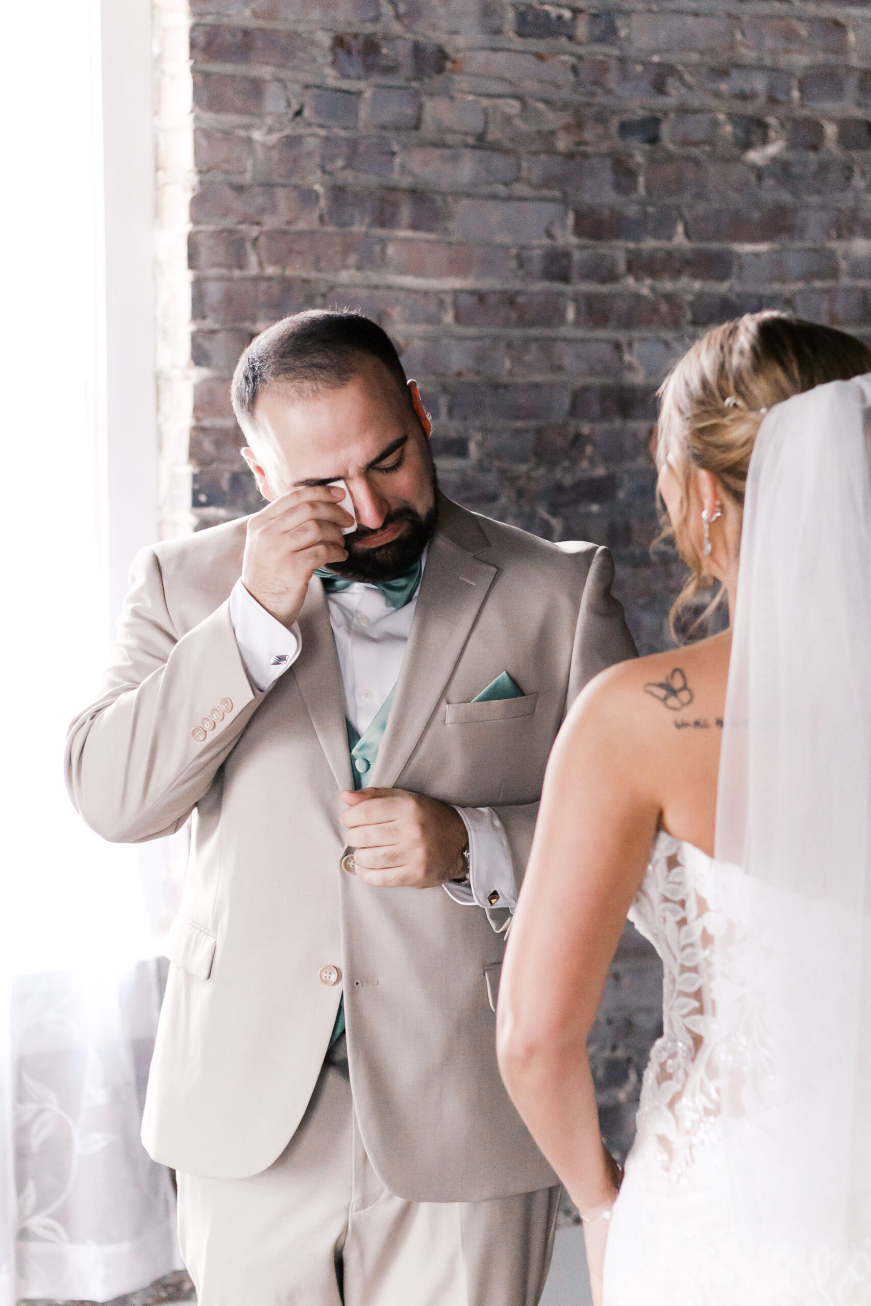 Groom wiping his eye during an emotional indoor first look with the bride.