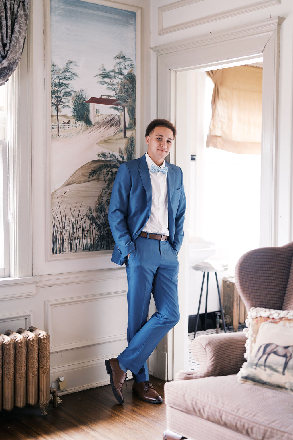 Groom in a light blue suit posing inside  historic wedding venue Longview Mansion before the ceremony.
