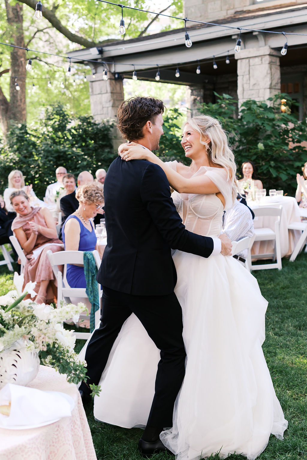 Bride and groom dancing together outdoors during their wedding reception at Simpson House surrounded by guests.
