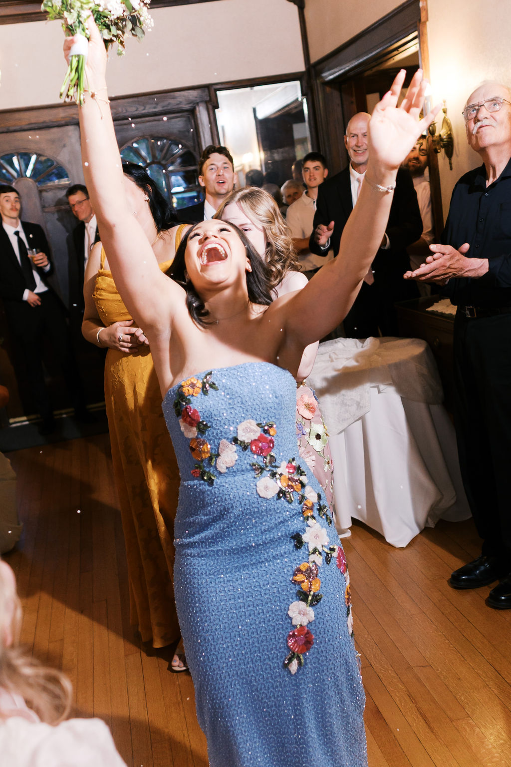 Wedding guest celebrating after catching the bridal bouquet during the reception at Simpson House