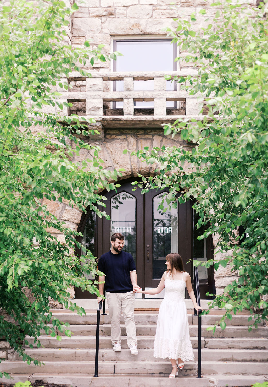 Couple holding hands on the front steps of The Truitt during engagement photos.