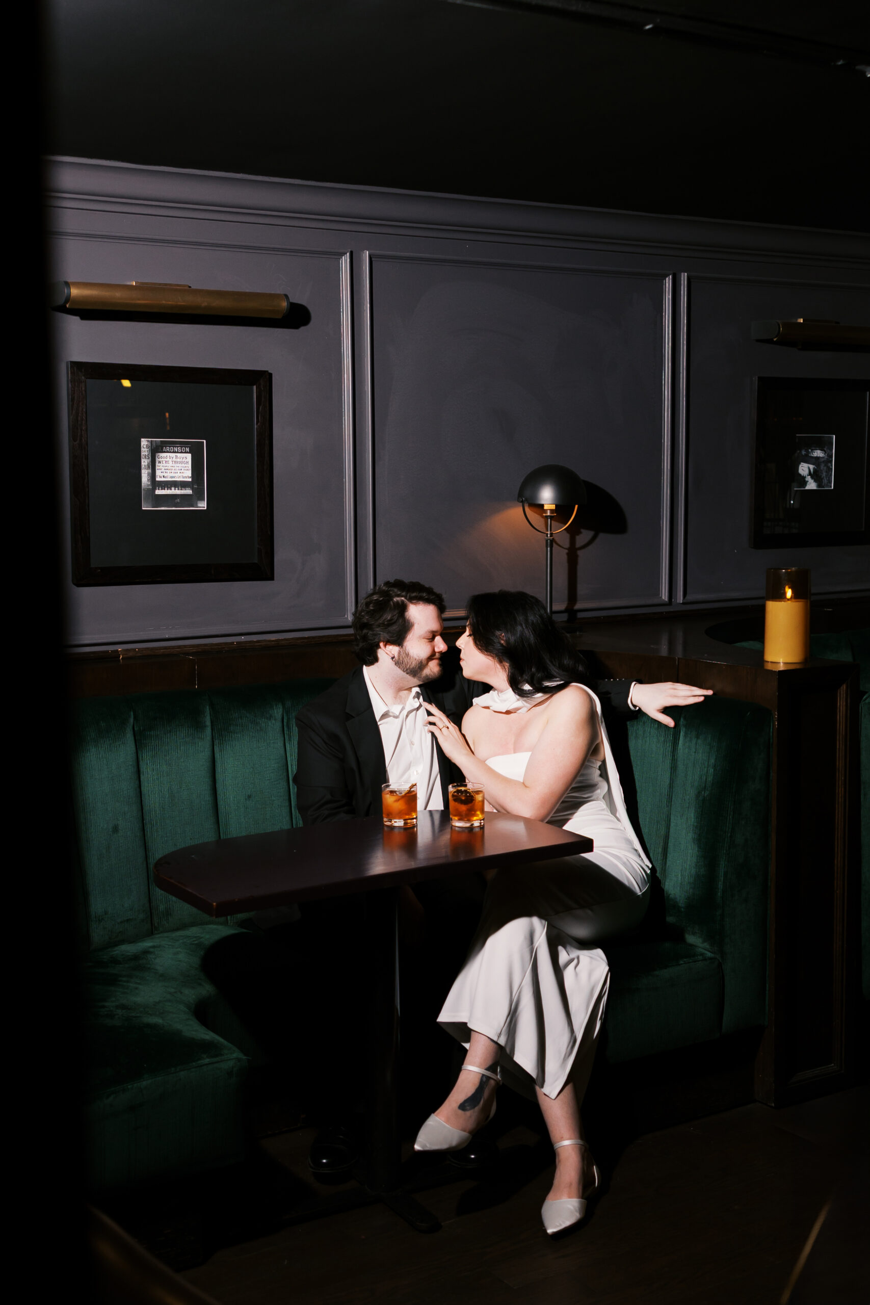 Couple sitting in a green velvet booth at Hotel Phillips in Kansas City, sharing a quiet moment over cocktails.