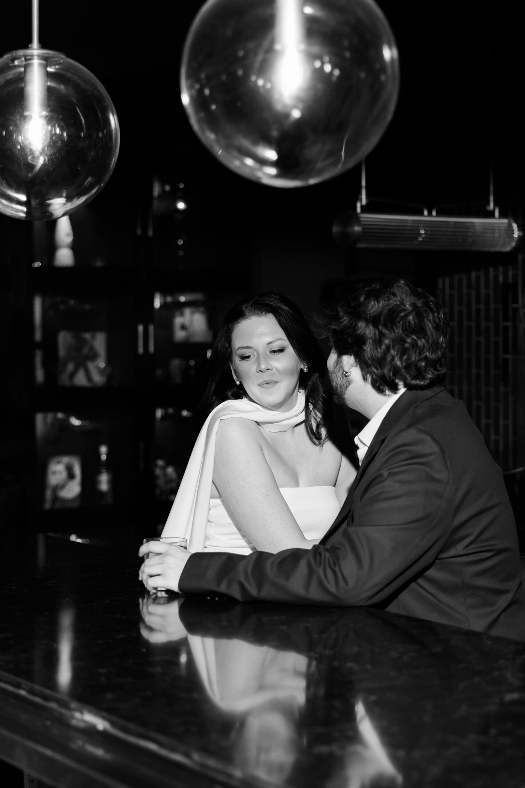 Black-and-white portrait of the couple talking together at the hotel bar.
