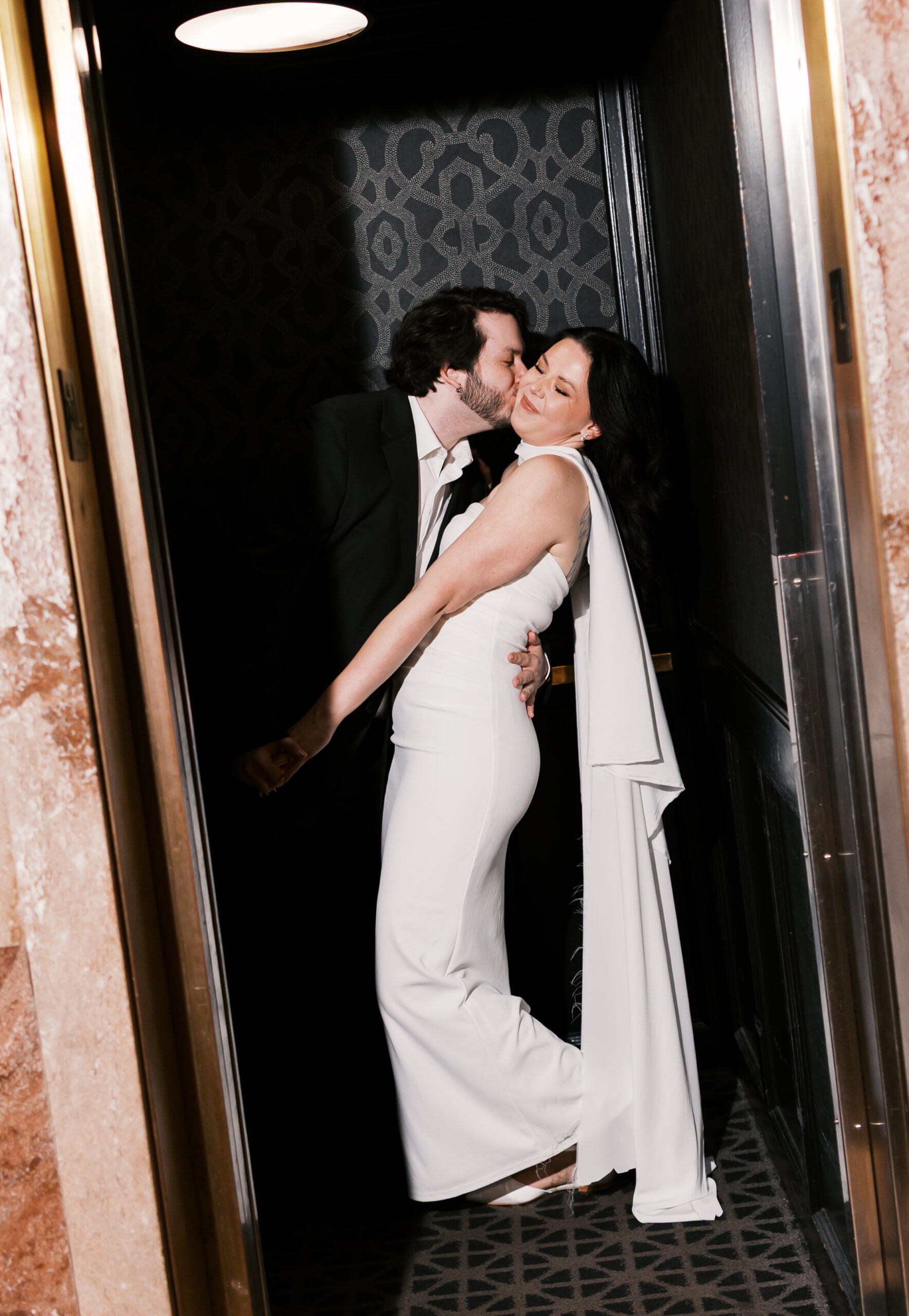 Couple embracing in an elevator doorway during their Hotel Phillips engagement session.