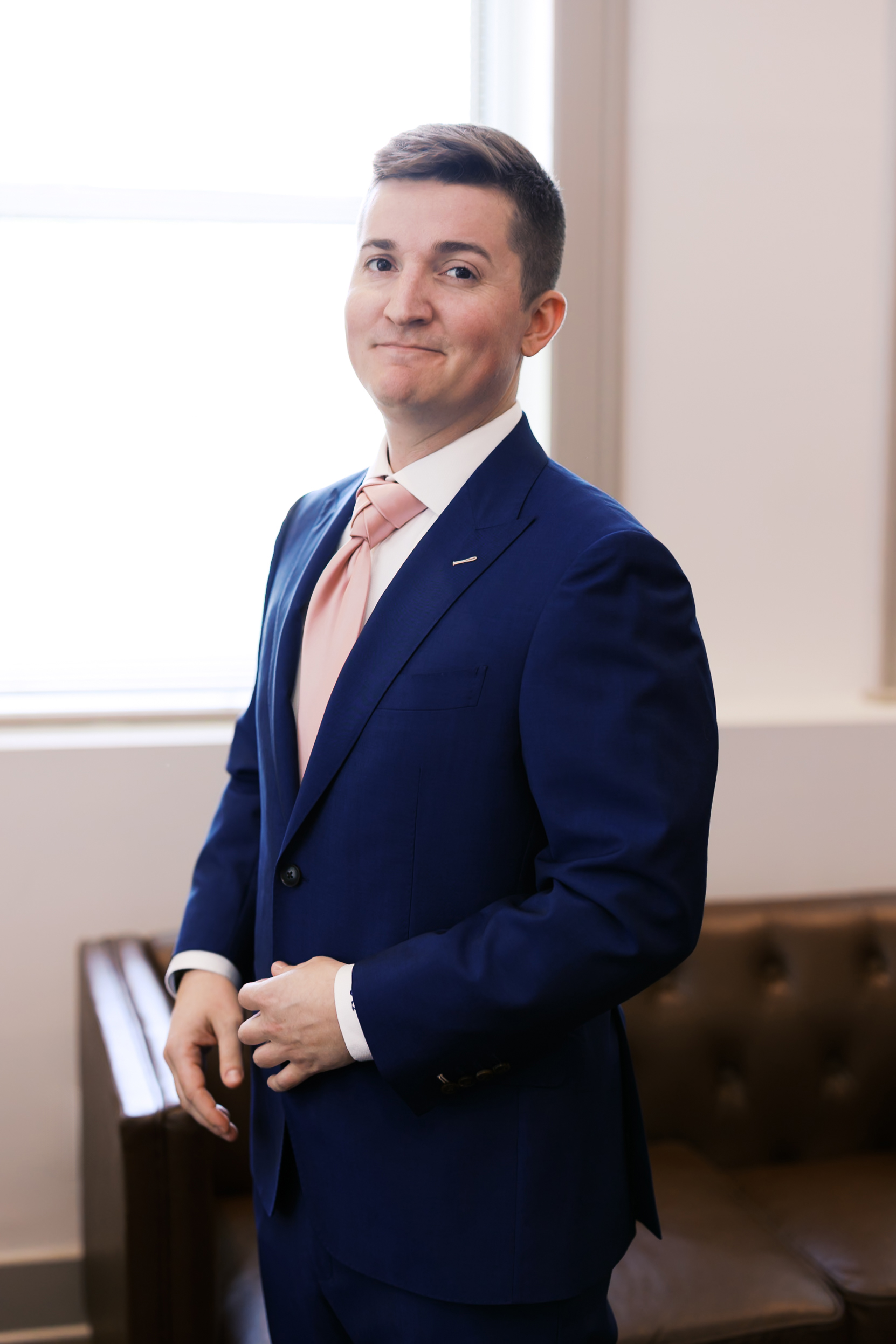 Portrait of the groom in a royal blue suit and blush pink tie inside The Loretto before the ceremony.