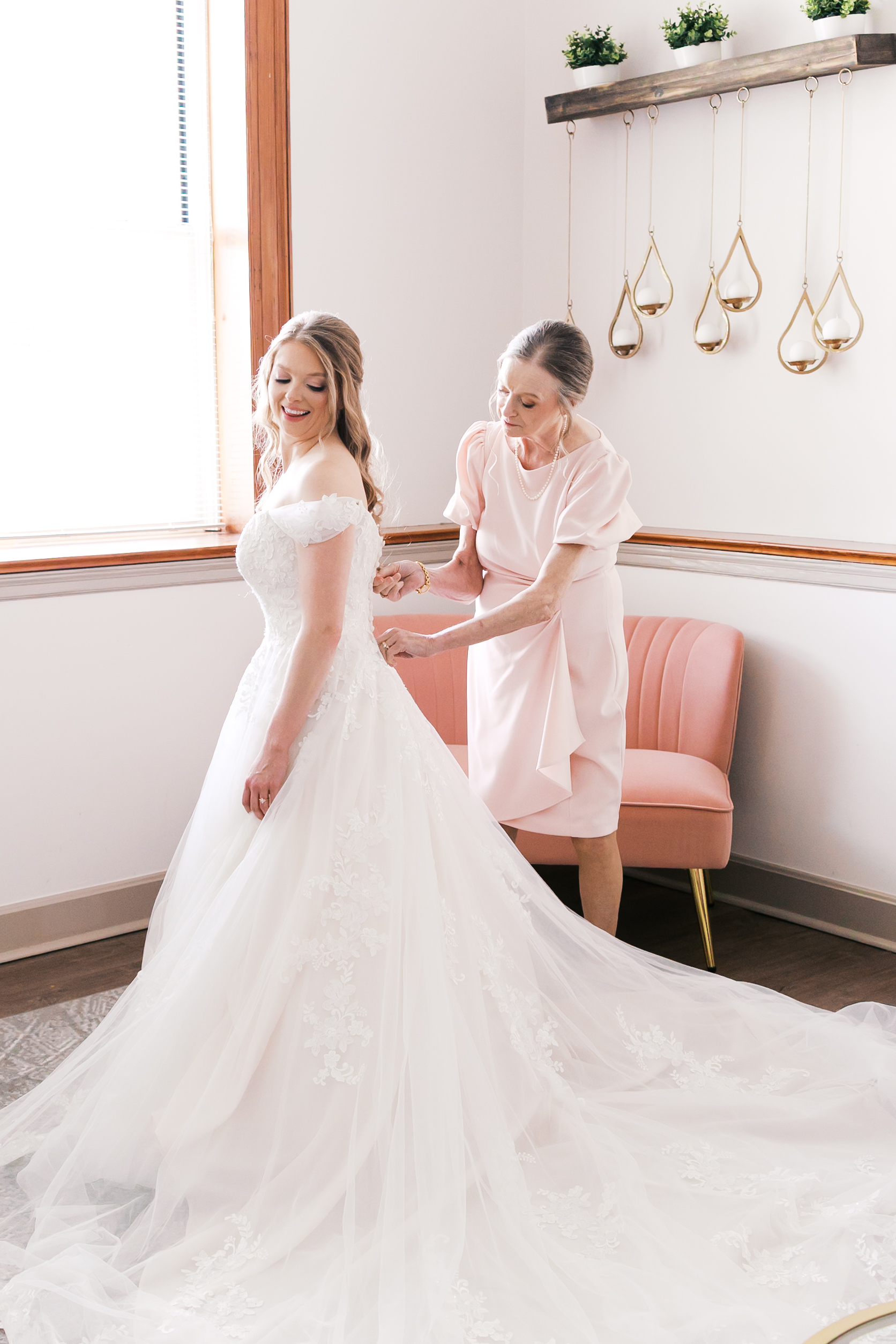 Mother helping button the bride's wedding dress in a bright bridal suite at The Loretto.