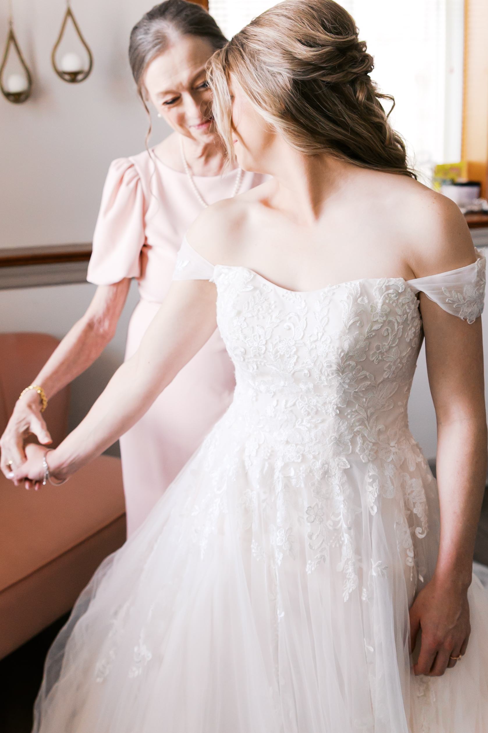Bride and her mother holding hands while sharing a quiet moment before the wedding ceremony.